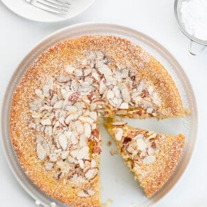 Almond Cake on a White Surface with Plates and Confectioners Sugar and a Slice Removed. Almond Cake, French Almond Cake, Moist Almond Cake, How to Make Almond Cake, Almond Cake Recipes, Easy Almond Cake Recipes, Baking, Dessert, Holiday Baking, Christmas Cake, Thanksgiving Cake, i am baker, iambaker