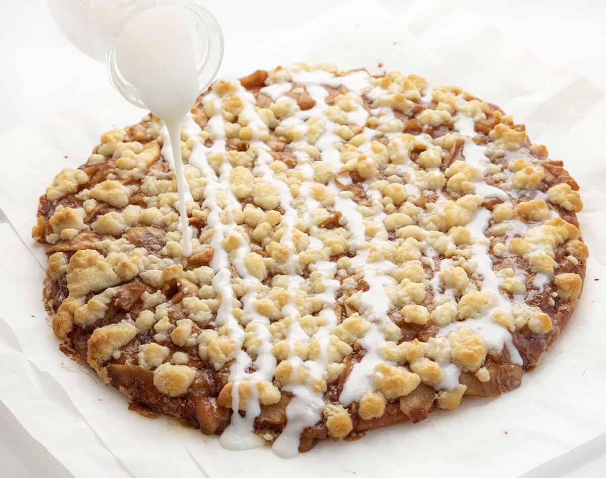 Apple Dessert Pizza is a sweet, soft dessert pizza that is topped with a homemade apple pie filling, cinnamon butter topping, and a sweet glaze. Apple Cactus Bread - Apple Dessert Pizza, Dessert Pizza, 2 Ingredient Pizza Dough, How to Make Cactus Bread, pizza dough dessert pizza, i am baker, iambaker, desserts, baking Adding Glaze to Apple Cactus Bread - Apple Dessert Pizza