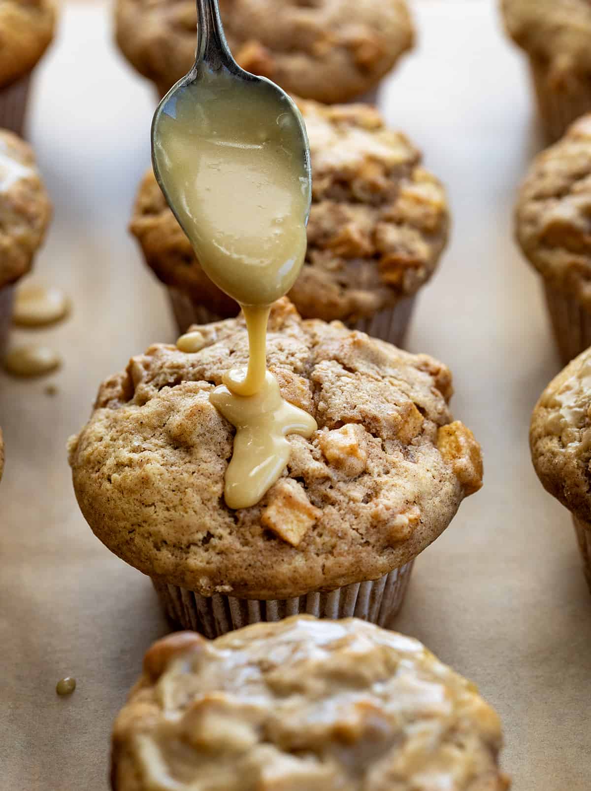 Old Fashioned Apple Muffins are moist, dense muffins loaded with apples and drizzled with a maple glaze, perfect for breakfast, brunch, or as a delightful dessert option. Enjoy the comforting flavors of fall and the sweetness of maple in every delicious bite! Drizzling Maple Glaze Over Freshly Baked Apple Muffins.