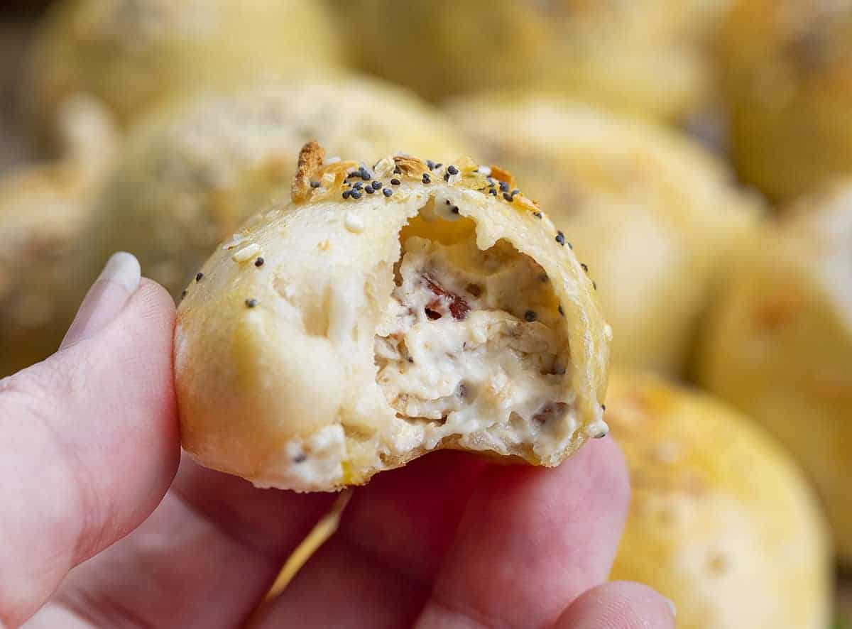 Stuffed Bagel Bites are pieces of pizza dough wrapped around a cream cheese and bacon mixture, topped with an egg wash and everything seasoning. Appetizer, Bagel Bites, Easy Homemade bagel Bites, Hw to Make Bagel Bites, Starbucks Recipes, i am baker, iambaker, recipes, air fryer bagel bites Hand Holding Bagel Bites - Starbucks Copycat Recipe