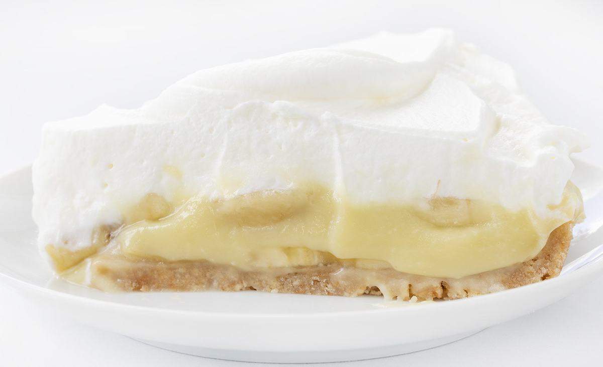 The best no-bake desserts to get your sweet tooth through the summer! no bake, no bake desserts, desserts, recipes, cheesecake, cookies, bars, cake, pudding, mousse, puppy chow, muddie buddies, rice krispy bars, dessert, memorial day dessert, labor day desserts, i am baker, iambaker One Slice of Banana Cream Pie on a White Plate.