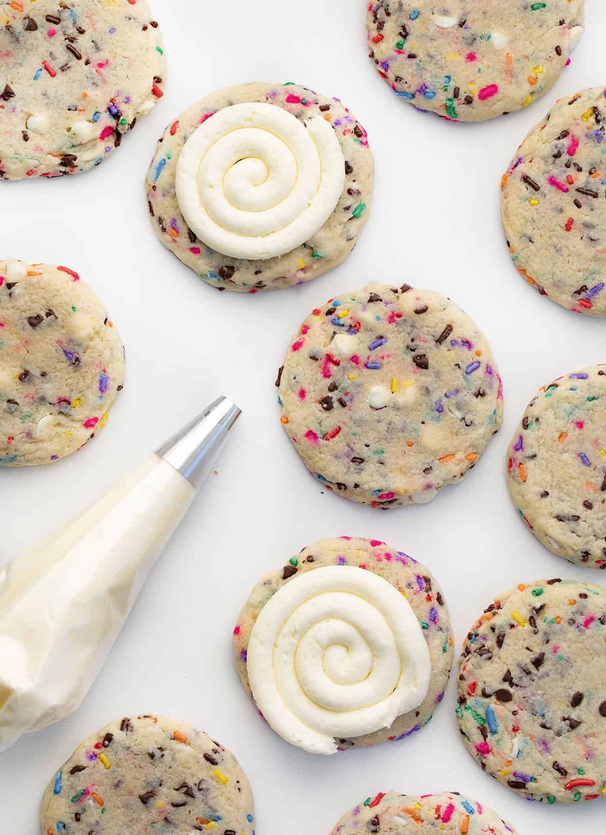 Birthday Cookies are chilled, but soft cookies that are loaded with colorful sprinkles, both chocolate and white chocolate chips, and topped with buttercream frosting. Cookies, Baking, Dessert, Birthday Cookies, Cookies with Frosting, Crumbl copycat cookie, birthday cookie recipes, cookie recipes, i am baker, iambaker Adding Buttercream Frosting in a Swirl to Birthday Cake Cookies