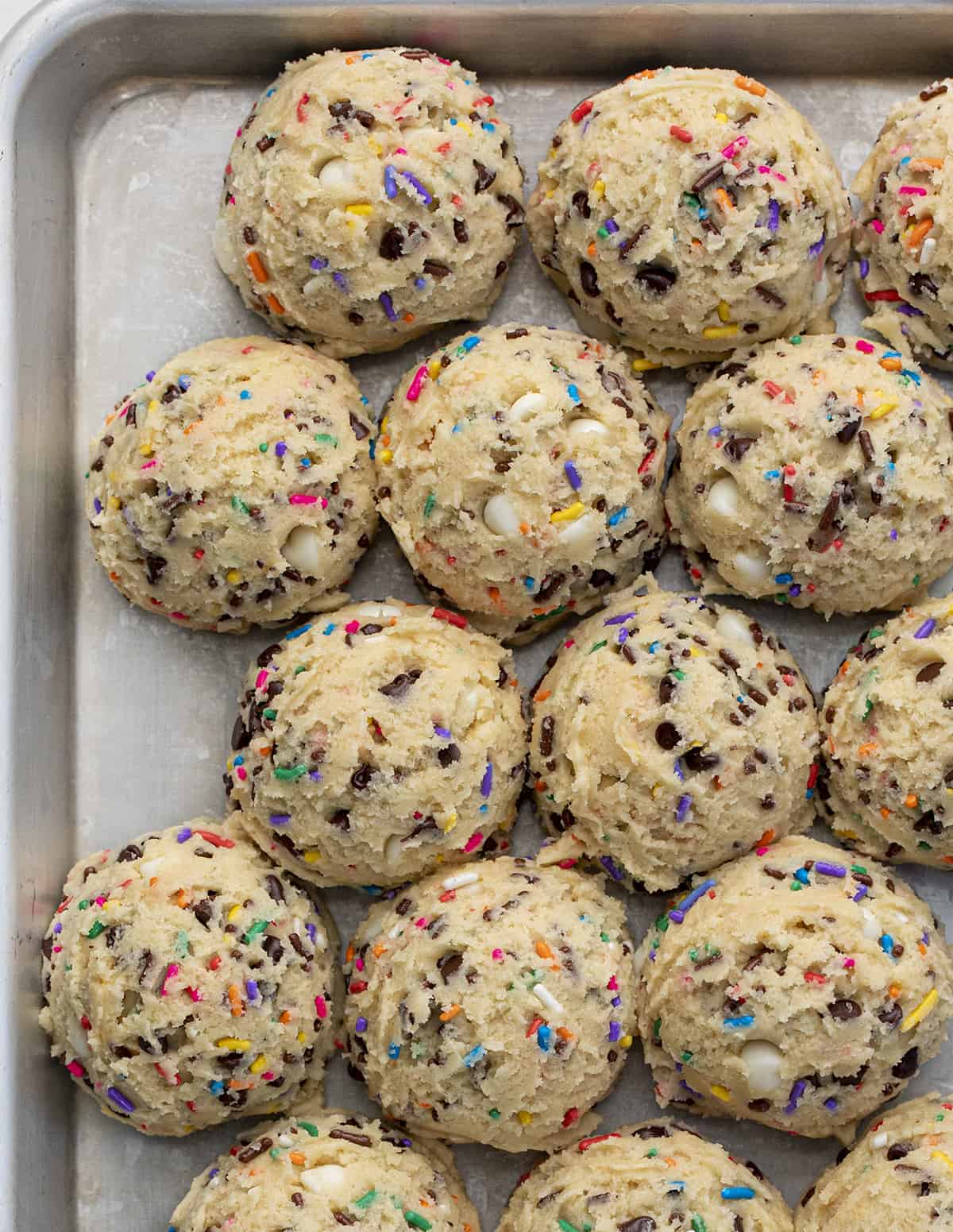 Birthday Cookies are chilled, but soft cookies that are loaded with colorful sprinkles, both chocolate and white chocolate chips, and topped with buttercream frosting. Cookies, Baking, Dessert, Birthday Cookies, Cookies with Frosting, Crumbl copycat cookie, birthday cookie recipes, cookie recipes, i am baker, iambaker Tray of Birthday Cake Cookie Dough Balls