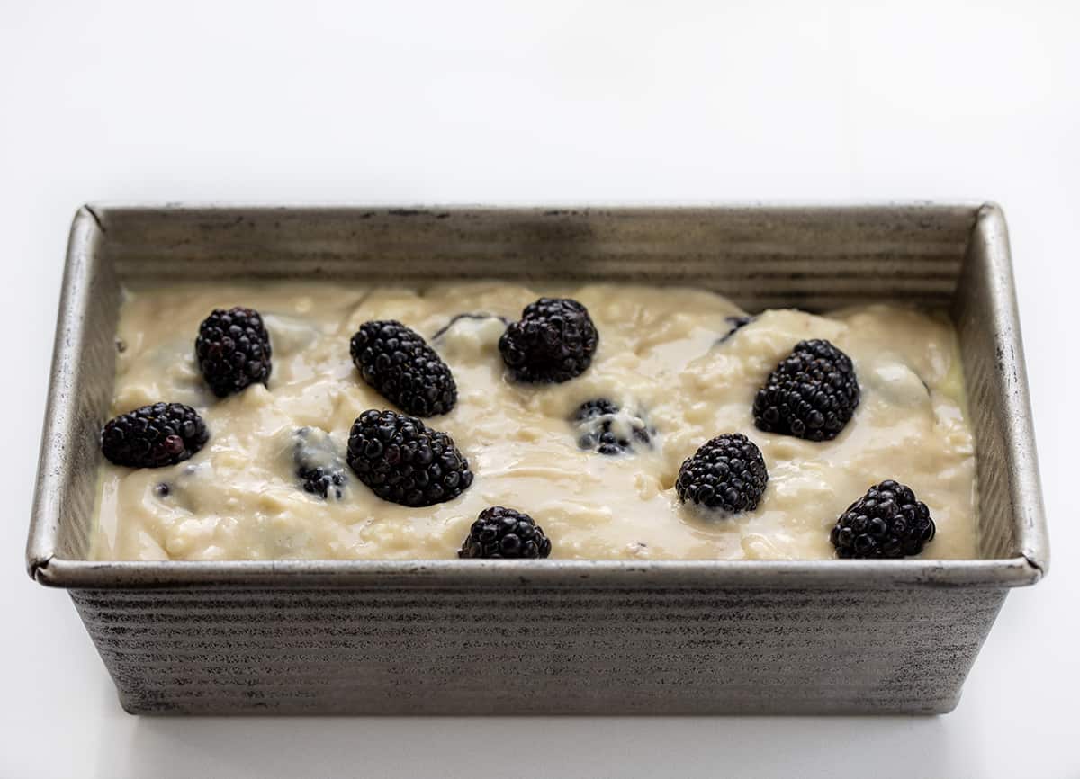Blackberry Loaf is a soft and tender quick bread loaded with fresh blackberries and drizzled with an optional sweet glaze. Whether you're planning a casual brunch, afternoon tea, or simply a gathering with friends, this blackberry loaf fits the occasion perfectly! Plus, it is easy to make! I like to pair a slice with a cup of coffee for a delightful snack. Raw Batter for Blackberry Loaf in a Pan on a White Counter.