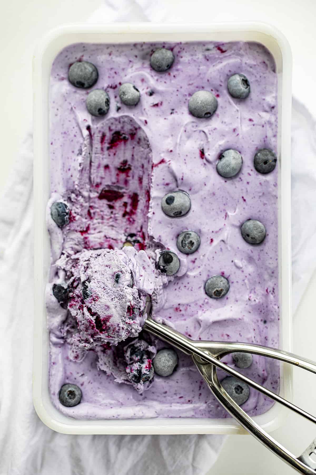 Blueberry No-Churn Ice Cream is super flavorful homemade ice cream made with fresh blueberries. The best part? No ice cream machine is required! Homemade Ice Cream, No Churn Ice Cream, Blueberry No Churn Ice Cream, Fresh Blueberry Ice Cream, Fruity Ice Cream, Dessert, No Bake Dessert, Blueberry Desserts, Easy Dessert, recipes, i am baker, iambaker Scoop with Blueberry No-Churn Ice Cream in It Resting on Ice Cream from Overhead.