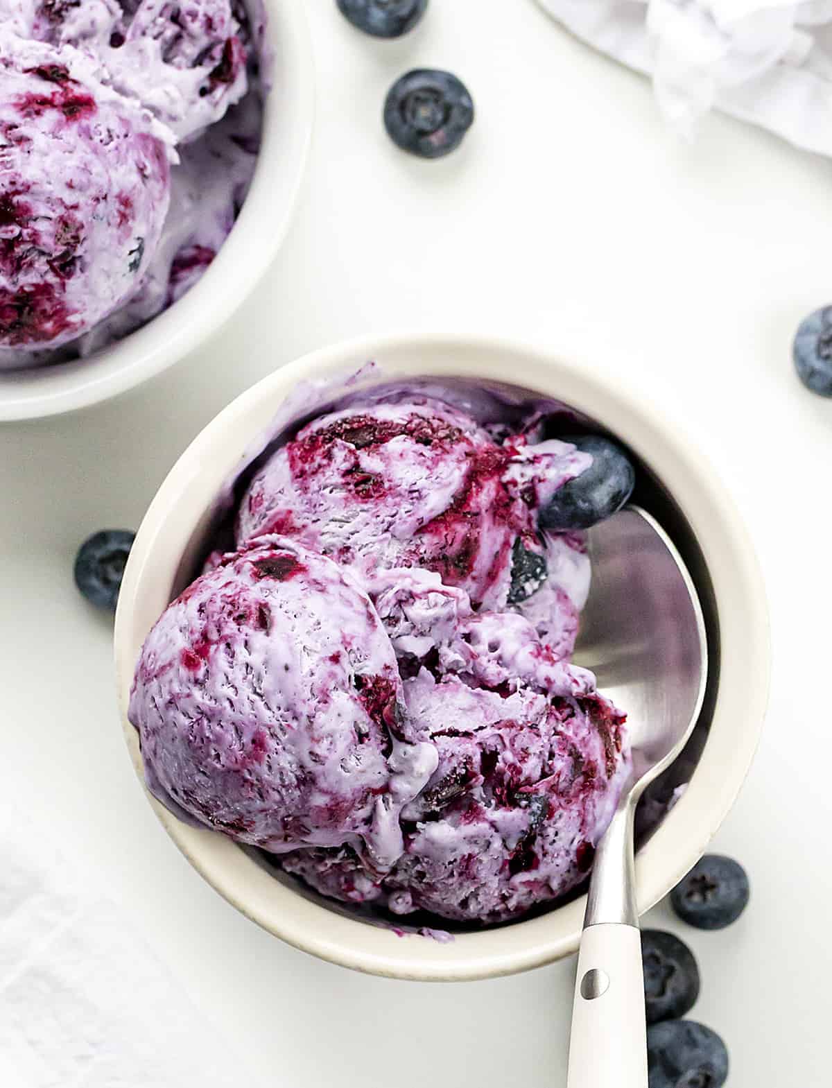 Blueberry No-Churn Ice Cream is super flavorful homemade ice cream made with fresh blueberries. The best part? No ice cream machine is required! Homemade Ice Cream, No Churn Ice Cream, Blueberry No Churn Ice Cream, Fresh Blueberry Ice Cream, Fruity Ice Cream, Dessert, No Bake Dessert, Blueberry Desserts, Easy Dessert, recipes, i am baker, iambaker Two Bowls of Blueberry No-Churn Ice Cream with Spoon from Overhead.