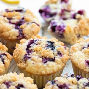Blueberry Lemon Muffins on a White Counter with Fresh Lemon Slice and Blueberries.