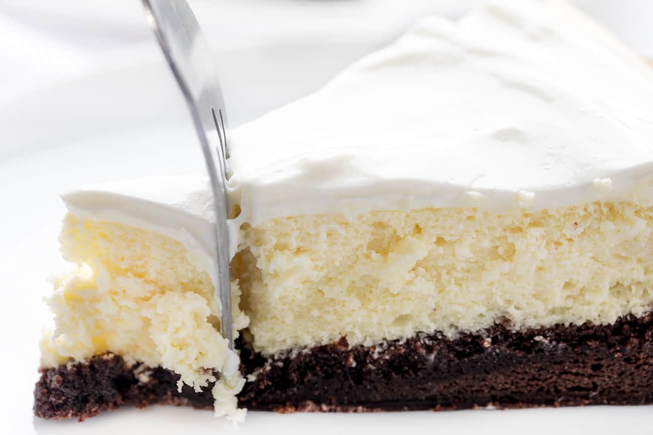 Brownie Bottom Cheesecake is a rich and creamy cheesecake that is layered on top of a sweet chocolate brownie mixture bottom, covered with a sweet sour cream topping! Cheesecake, Brownie Bottom Cheesecake, Brownie Cheesecake, Dessert, Baking, How to Make Brownie Bottom Cheesecake, How to Make Sour Cream Glaze, i am baker, iambaker Side View of Brownie Bottom Cheesecake with Fork Inserted and Removing the Tip