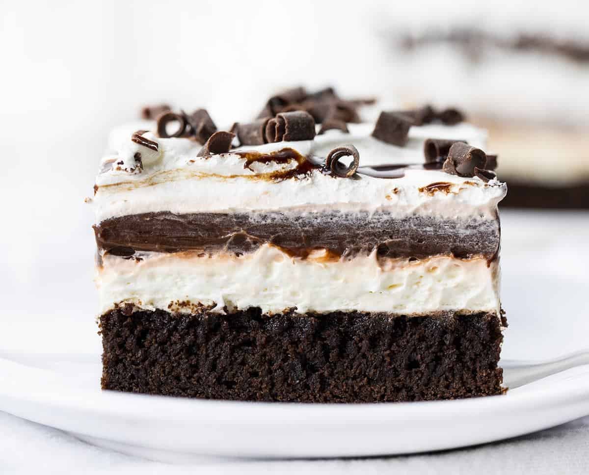 Brownie Pudding Dessert is a decadent layered dessert that starts with the perfect brownie, topped with a cream cheese and chocolate pudding layer, finished off with cool whip and more chocolate! Brownie, Chocolate Pudding, Brownie Pudding Dessert, Brownie Dessert, Dessert, Pudding Dessert, Summer Desserts, Fall Desserts, Winter Dessert, Dessert Recipes, Brownie Recipes, Layered Dessert, i am baker, iambaker One Brownie Pudding Dessert Piece on a Plate Showing Individual Layers