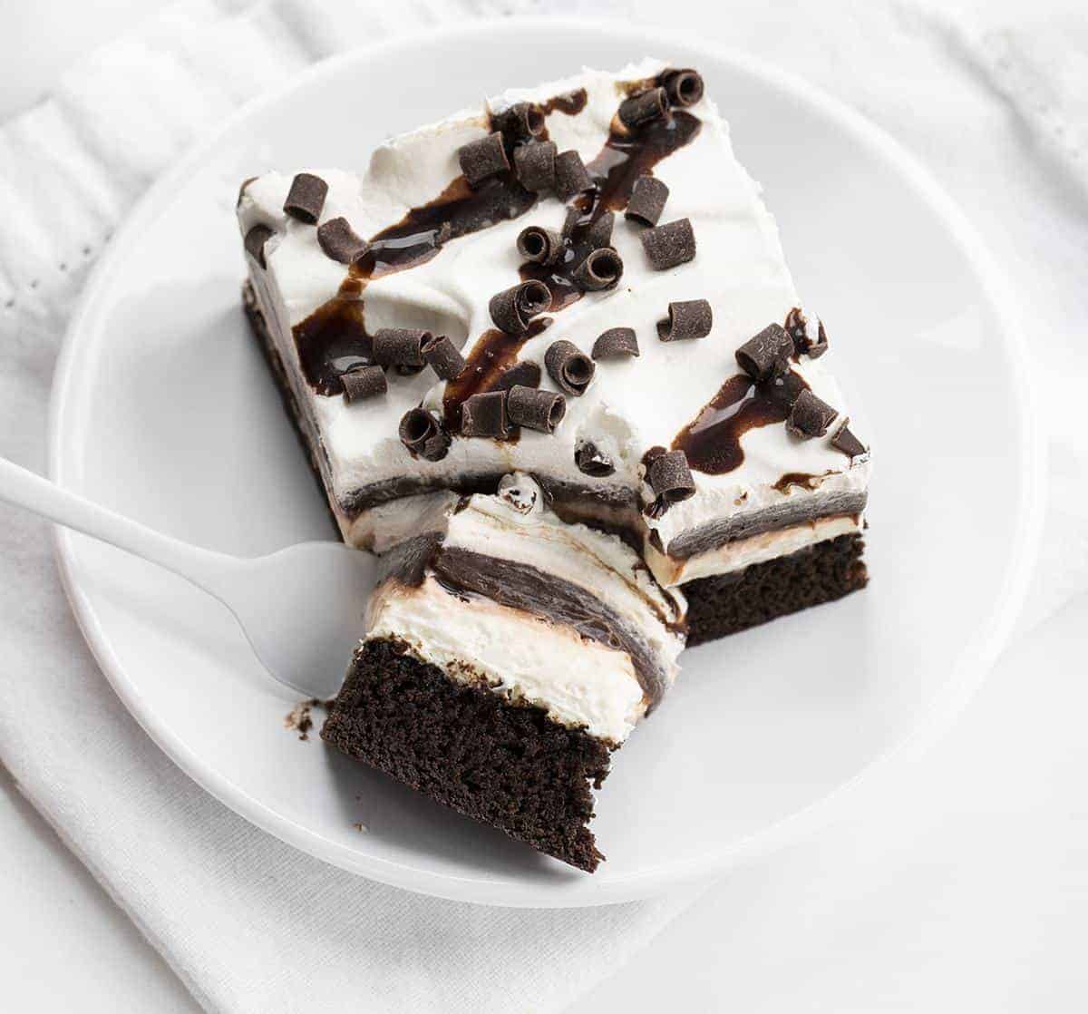 Brownie Pudding Dessert is a decadent layered dessert that starts with the perfect brownie, topped with a cream cheese and chocolate pudding layer, finished off with cool whip and more chocolate! Brownie, Chocolate Pudding, Brownie Pudding Dessert, Brownie Dessert, Dessert, Pudding Dessert, Summer Desserts, Fall Desserts, Winter Dessert, Dessert Recipes, Brownie Recipes, Layered Dessert, i am baker, iambaker Forkful of Brownie Pudding Dessert on White Plate