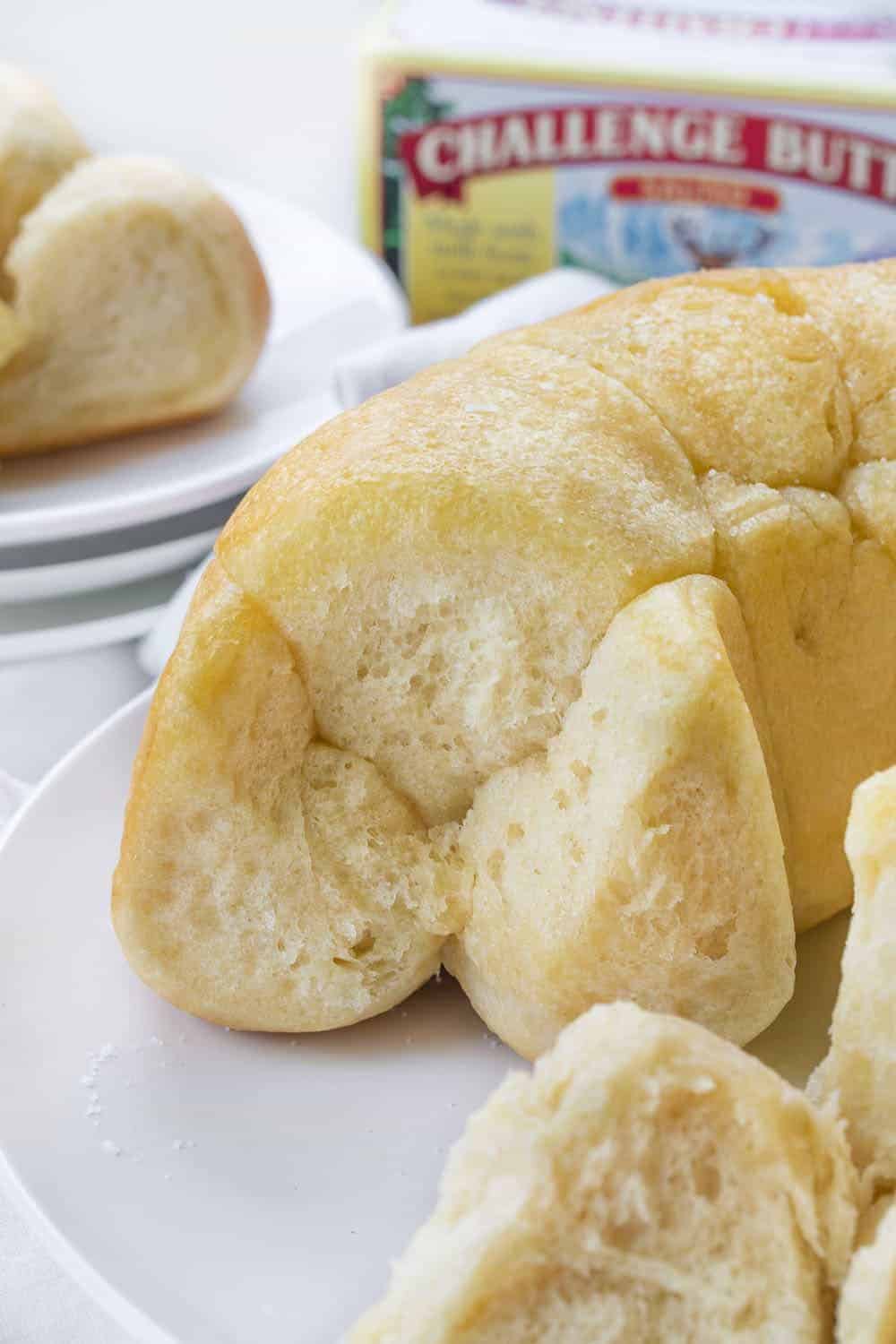 Buttery Bubble Bread is homemade bread that is a soft, salty, and buttery pull-apart bread that is easy to make and perfect for dinner rolls! Butter Bread, Bubble Bread, Buttery Bubble Bread, Bundt Bread, Dinner Rolls, Thanksgiving, Christmas rolls, bread recipe, homemade bread, rolls, i am baker, iambaker, recipes Bubble Bread Recipe with Pieces Removed Showing Inside and Pieces on a Plate Behind