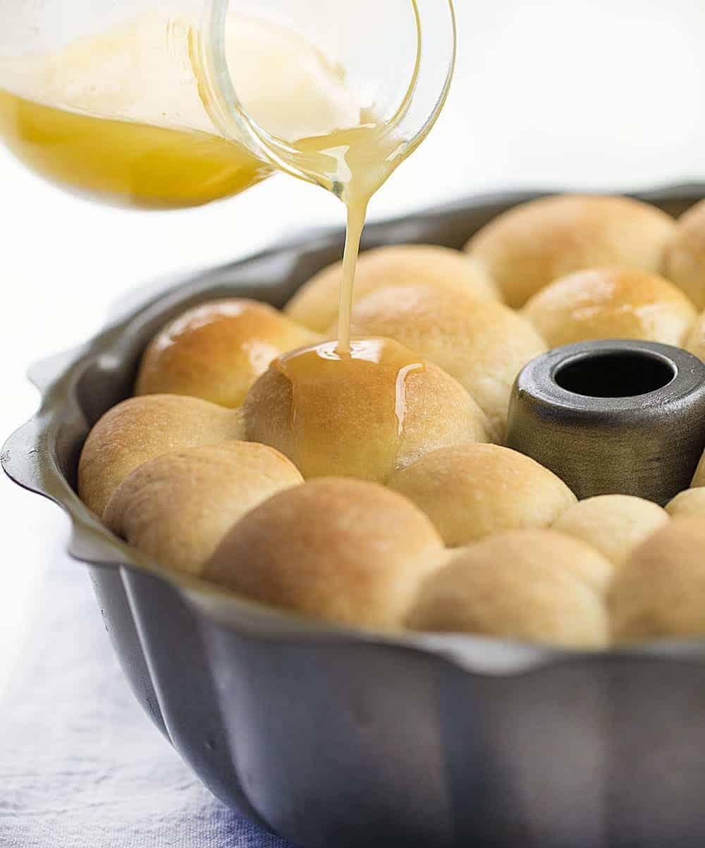 Buttery Bubble Bread is homemade bread that is a soft, salty, and buttery pull-apart bread that is easy to make and perfect for dinner rolls! Butter Bread, Bubble Bread, Buttery Bubble Bread, Bundt Bread, Dinner Rolls, Thanksgiving, Christmas rolls, bread recipe, homemade bread, rolls, i am baker, iambaker, recipes Pouring Butter over Bubble Bread in Bundt Pan