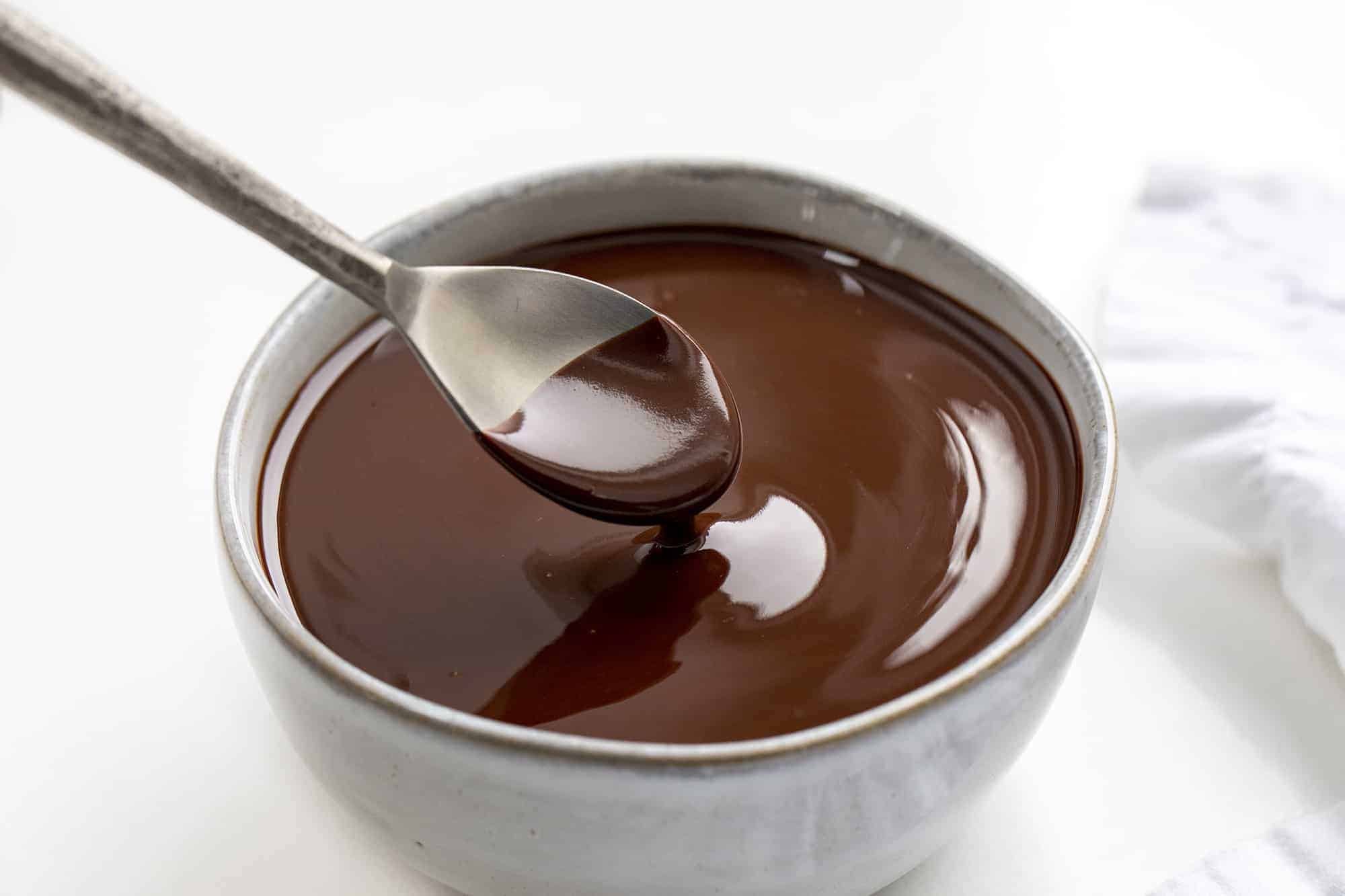 Chocolate Ganache made with Butter is semi-sweet chocolate melted with butter to create a rich and shiny chocolatey topping, glaze, icing, or filling. 2 ingredient ganache, two ingredient ganache, butter chocolate ganache, butter ganache, chocolate ganache, easy chocolate ganache, how to make ganache, the best butter ganache recipes, desserts, baking, chocolate, easter, new years eve, christmas ganache, i am baker, iambaker Spoon Picking up some smooth Butter Chocolate Ganache