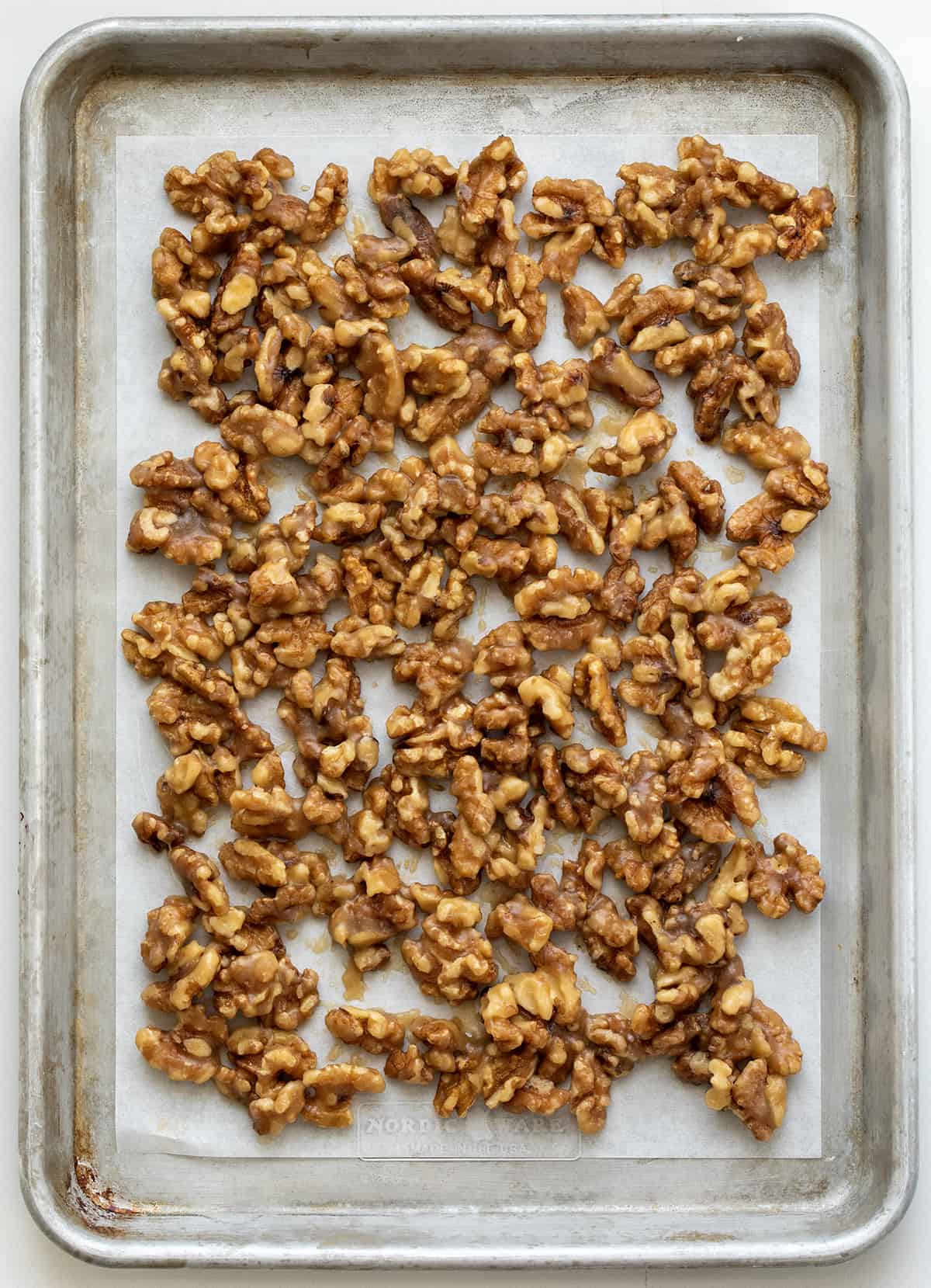 This is the ONLY candied walnut recipe you will ever need!! Candied Walnuts are walnuts that have been coated with a buttery sweet mixture and then baked to a crunchy golden brown. They are an addicting snack on their own, but also a delicious topping for salads and desserts. And, they can even be made in an air fryer! Pan of Candied Walnuts Before They are Baked.