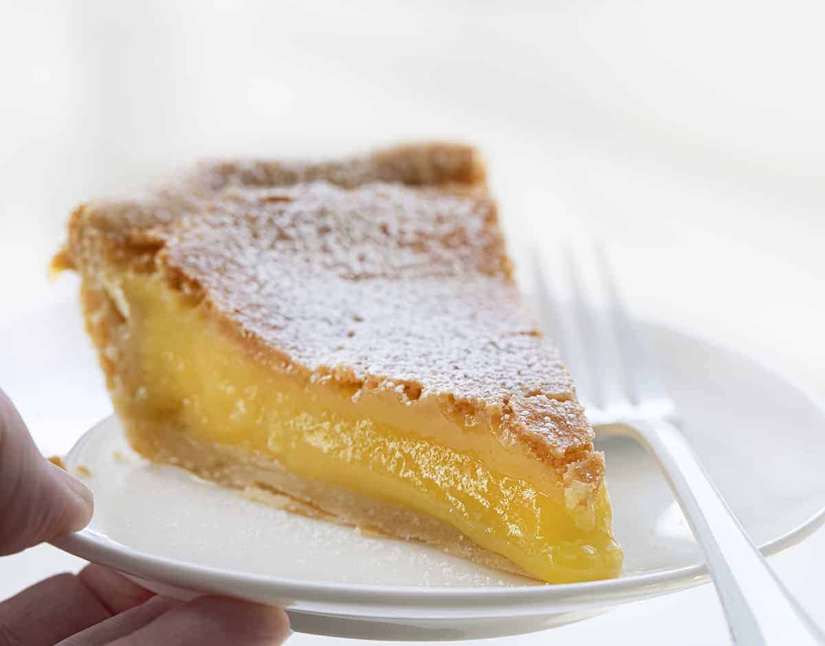 Chess Pie is a rich, sweet, and sugary classic pie that is made with ingredients you probably have on hand and baked in a flaky crust! Pie, Baking, Dessert, Chess Pie, Vintage Dessert, Classic Recipes, Classic Pie Recipes, Homemade Pie Crust, Rustic Pies, i am baker, iambaker Piece of Chess Pie Recipe on a White Plate with a White Fork