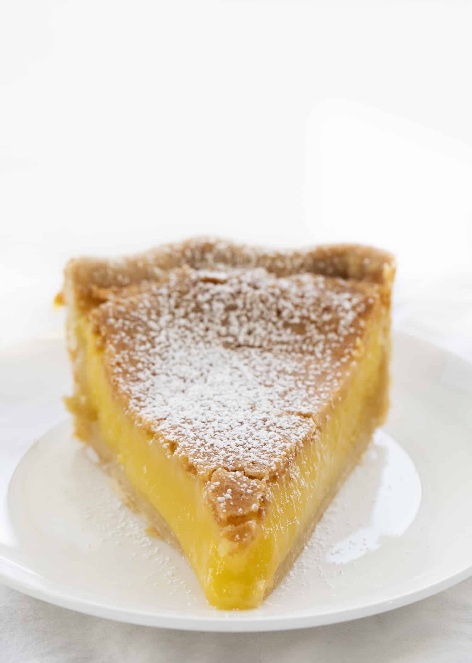Chess Pie is a rich, sweet, and sugary classic pie that is made with ingredients you probably have on hand and baked in a flaky crust! Pie, Baking, Dessert, Chess Pie, Vintage Dessert, Classic Recipes, Classic Pie Recipes, Homemade Pie Crust, Rustic Pies, i am baker, iambaker Piece of Chess Pie on a White Plate