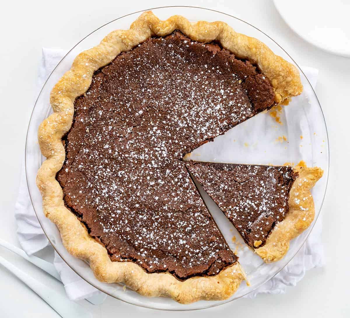 Chocolate Chess Pie is a fudgy chocolate pie filling made in a flaky crust that will satisfy all the chocolate lovers out there! The filling is thick, almost to the point of it being a brownie consistency. Lip smakin' delicious! Baking, Dessert, Chocolate Pie, Cheese Pie, Chocolate Chess Pie, Homemade Pie Crust, Store Bought Pie Crust, Easy Pie, Brownie Pie, Holiday Pie, Dessert Pie, Recipes, i am baker, iambaker Overhead of a Chocolate Chess Pie with a Piece removed and Another Piece Cut