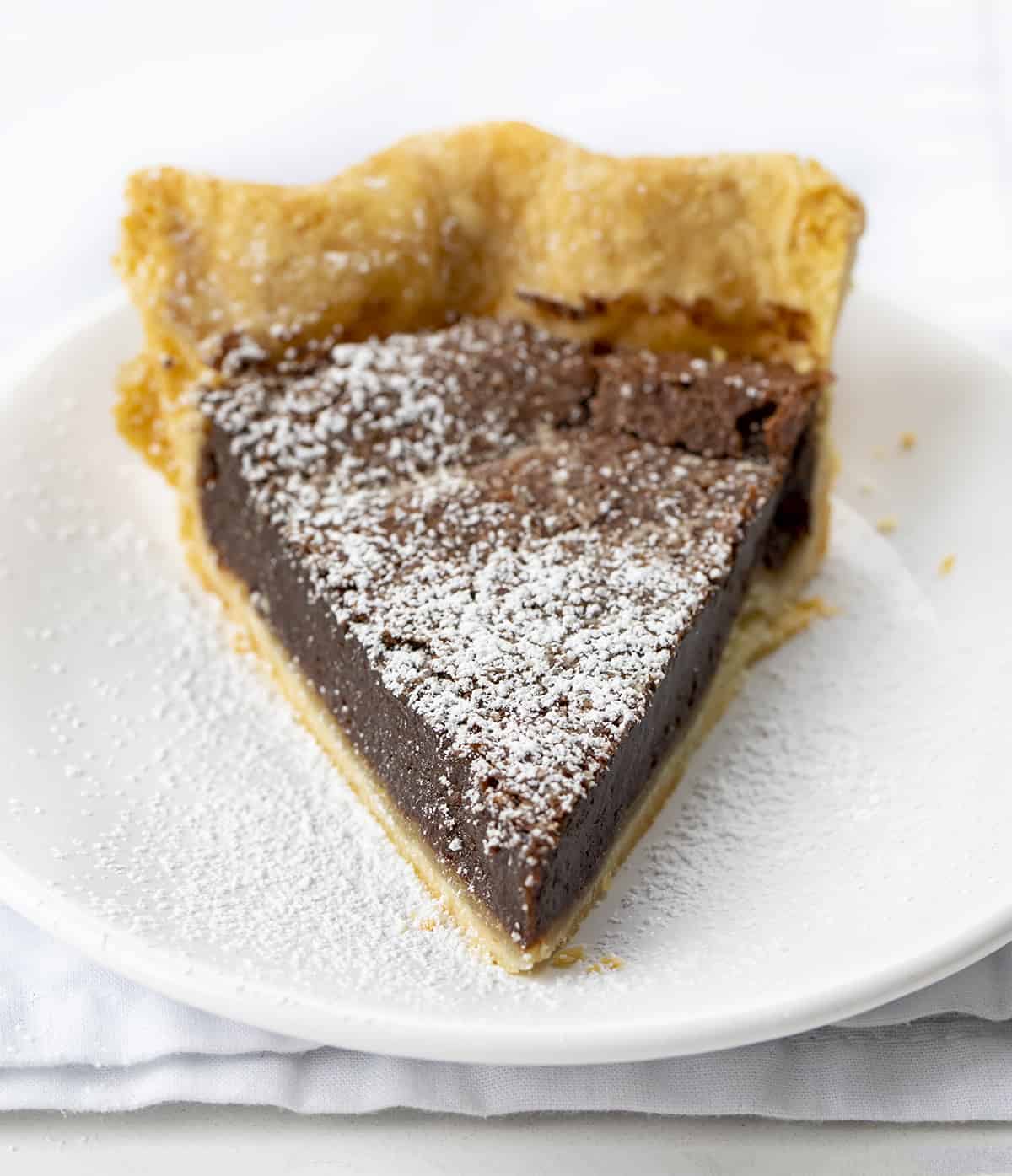 Chocolate Chess Pie is a fudgy chocolate pie filling made in a flaky crust that will satisfy all the chocolate lovers out there! The filling is thick, almost to the point of it being a brownie consistency. Lip smakin' delicious! Baking, Dessert, Chocolate Pie, Cheese Pie, Chocolate Chess Pie, Homemade Pie Crust, Store Bought Pie Crust, Easy Pie, Brownie Pie, Holiday Pie, Dessert Pie, Recipes, i am baker, iambaker One Piece of Chocolate Cheese Pie on a White Plate
