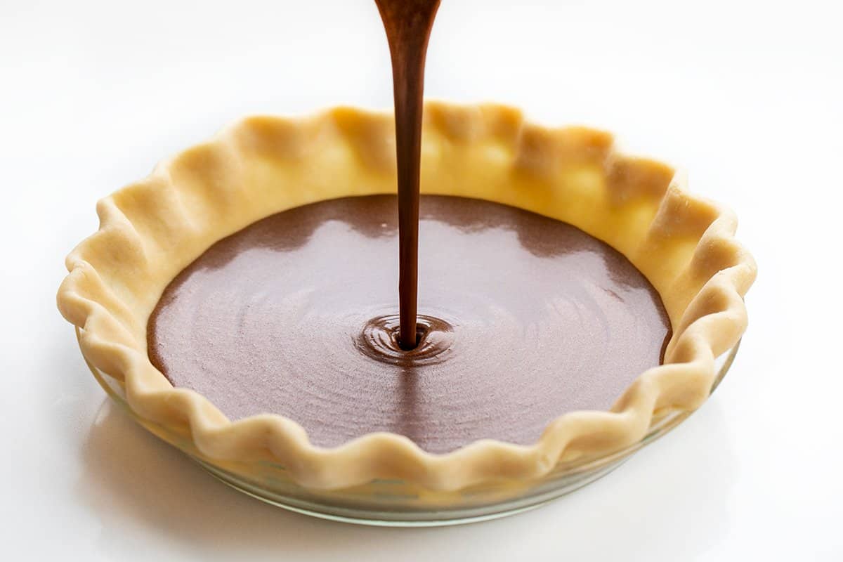 Chocolate Chess Pie is a fudgy chocolate pie filling made in a flaky crust that will satisfy all the chocolate lovers out there! The filling is thick, almost to the point of it being a brownie consistency. Lip smakin' delicious! Baking, Dessert, Chocolate Pie, Cheese Pie, Chocolate Chess Pie, Homemade Pie Crust, Store Bought Pie Crust, Easy Pie, Brownie Pie, Holiday Pie, Dessert Pie, Recipes, i am baker, iambaker Pouring Chocolate Cheese Pie Batter into a Pie Crust