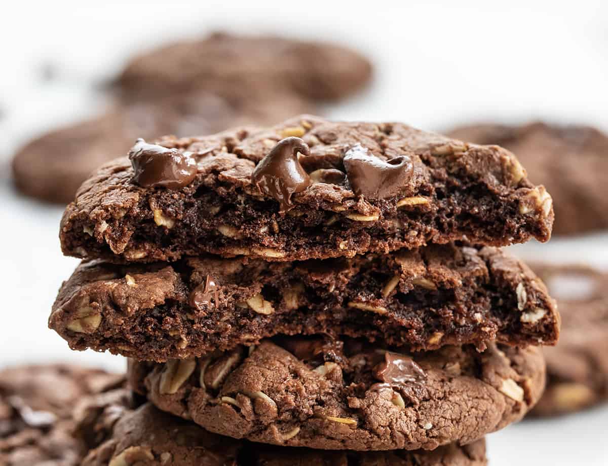 Chocolate Oatmeal Cookies are a delicious treat that has the perfect balance of chocolate and oats, creating a delightful texture and flavor combination. It is an oatmeal cookie with the earthy seasonings removed and then real chocolate added to the dough. The soft cookies can be enjoyed as an afternoon snack with a cup of coffee or tea or as a sweet dessert! Broken in Half Chocolate Oatmeal Cookies with Other Cookies Behind.