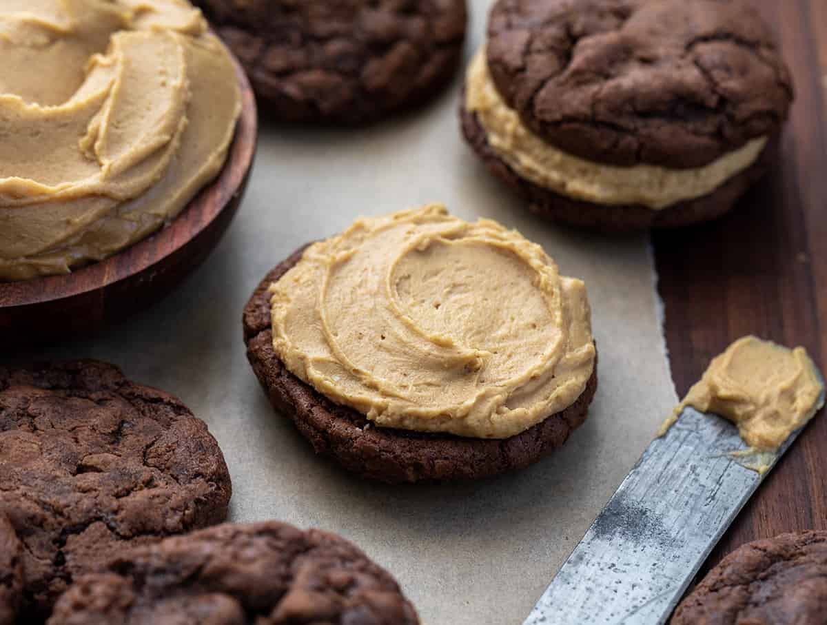 Chocolate Peanut Butter Sandwich Cookies are rich, chocolatey cookies filled with a homemade peanut butter frosting filling. The chocolate cookies are decadent enough to stand on their own with their crispy outside and soft, chewy center. (Trust me, I had a few!) But the added peanut butter filling was the perfect complement to the chocolate, making this one of my favorite sandwich cookies of all time. One Side of a Chocolate Peanut Butter Sandwich Cookies with the Peanut Butter Frosting Swirled on it Before Adding Other Cookie.