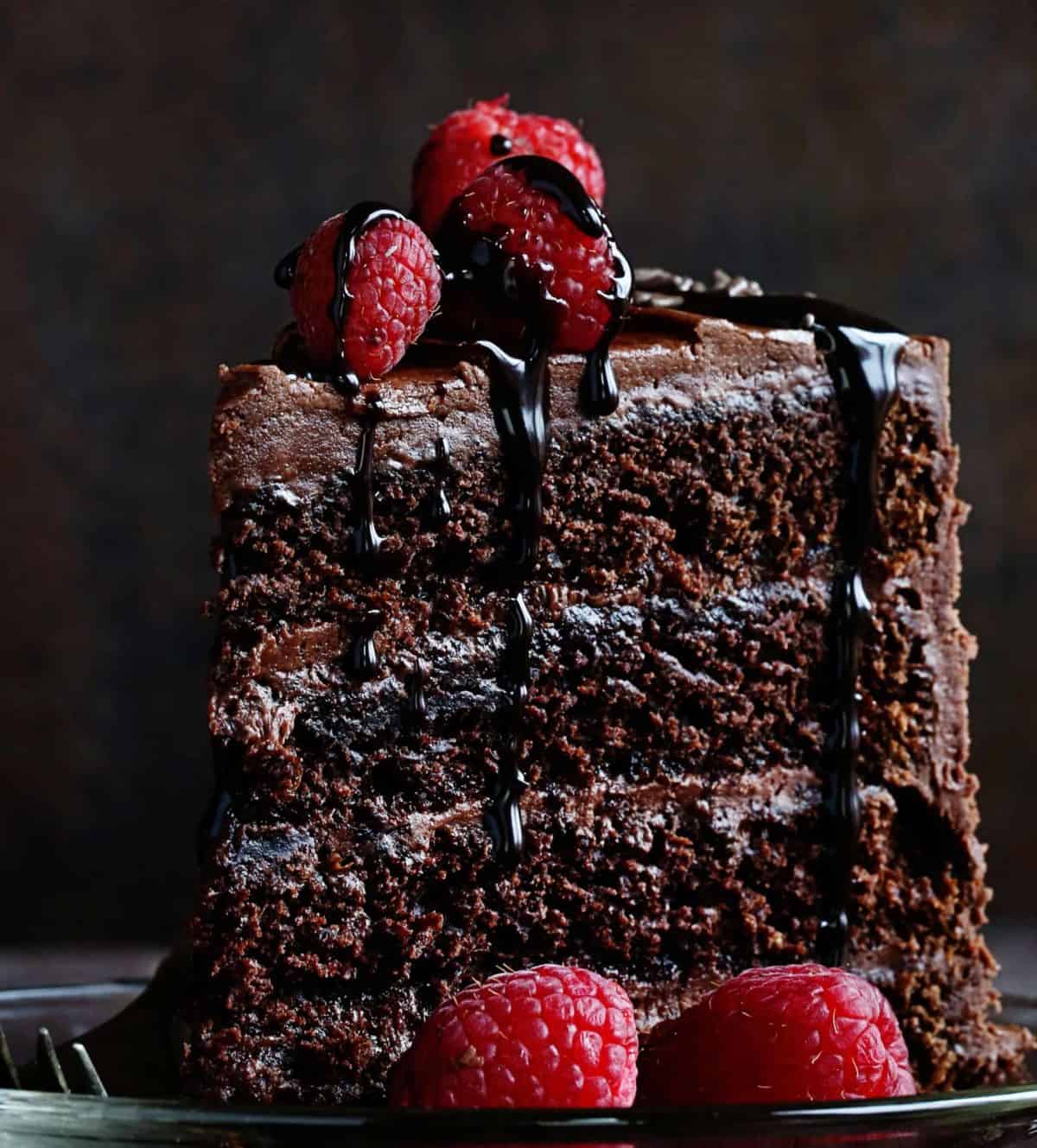 This Perfect chocolate cake has been handed down through generations! Baking, Chocolate Cake, Chocolate Frosting, Cake Decorating, Layer Cake, Dessert, Frosting, i am baker, iambaker, recipes Piece of Chocolate Cake on Plate with Raspberries