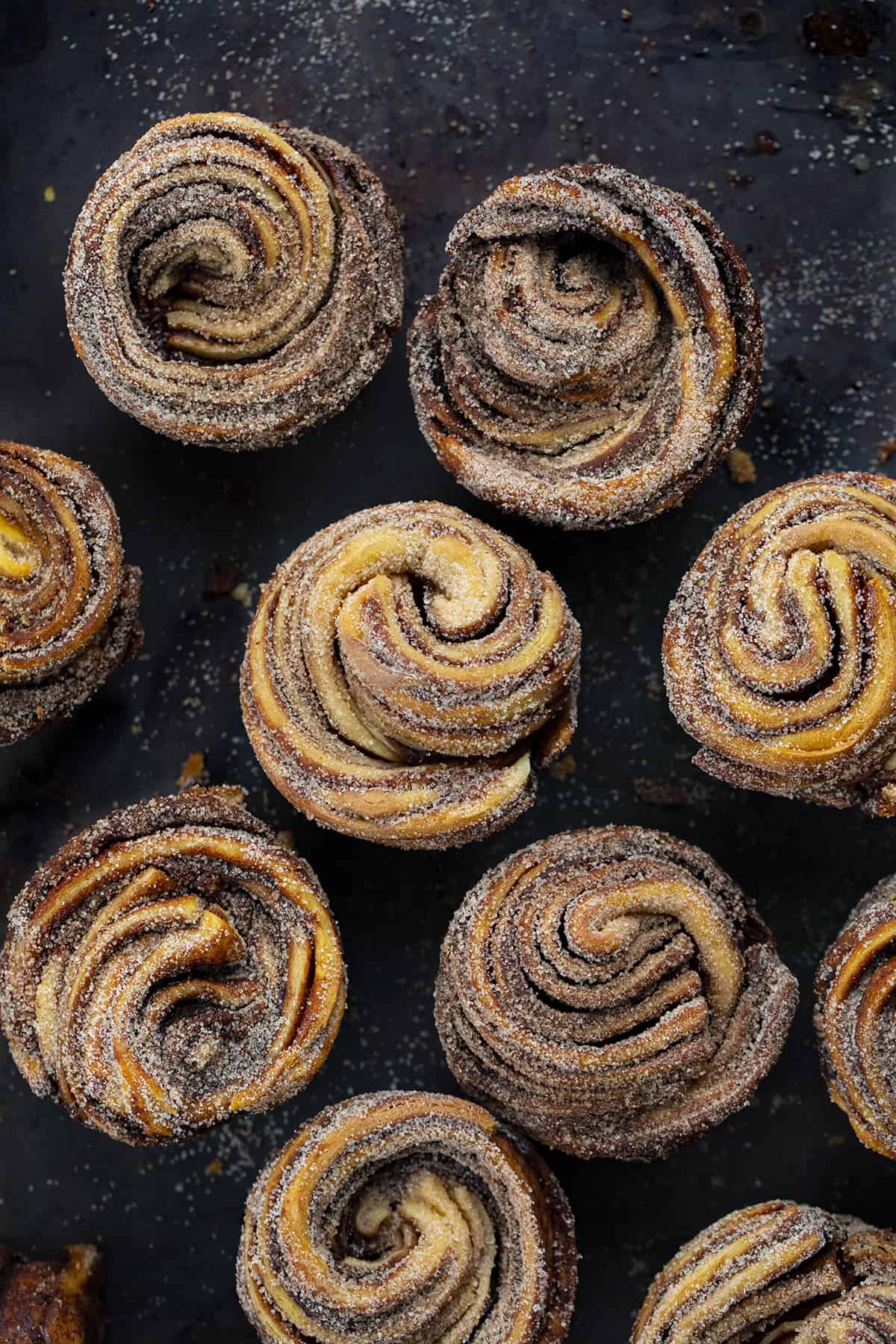 A cruffin is a cross between a croissant and a muffin that is rolled up like a cinnamon roll. It's a buttery, flaky dessert that is easier to make than it looks. Peppermint seems to be a part of the holidays, and these chocolate peppermint cruffins are no exception. In addition to the chocolate peppermint butter, I rolled each cruffin in more cocoa powder and sugar. They look fancy, but they are easy to make! Many Chocolate Peppermint Cruffins on a Black Counter.