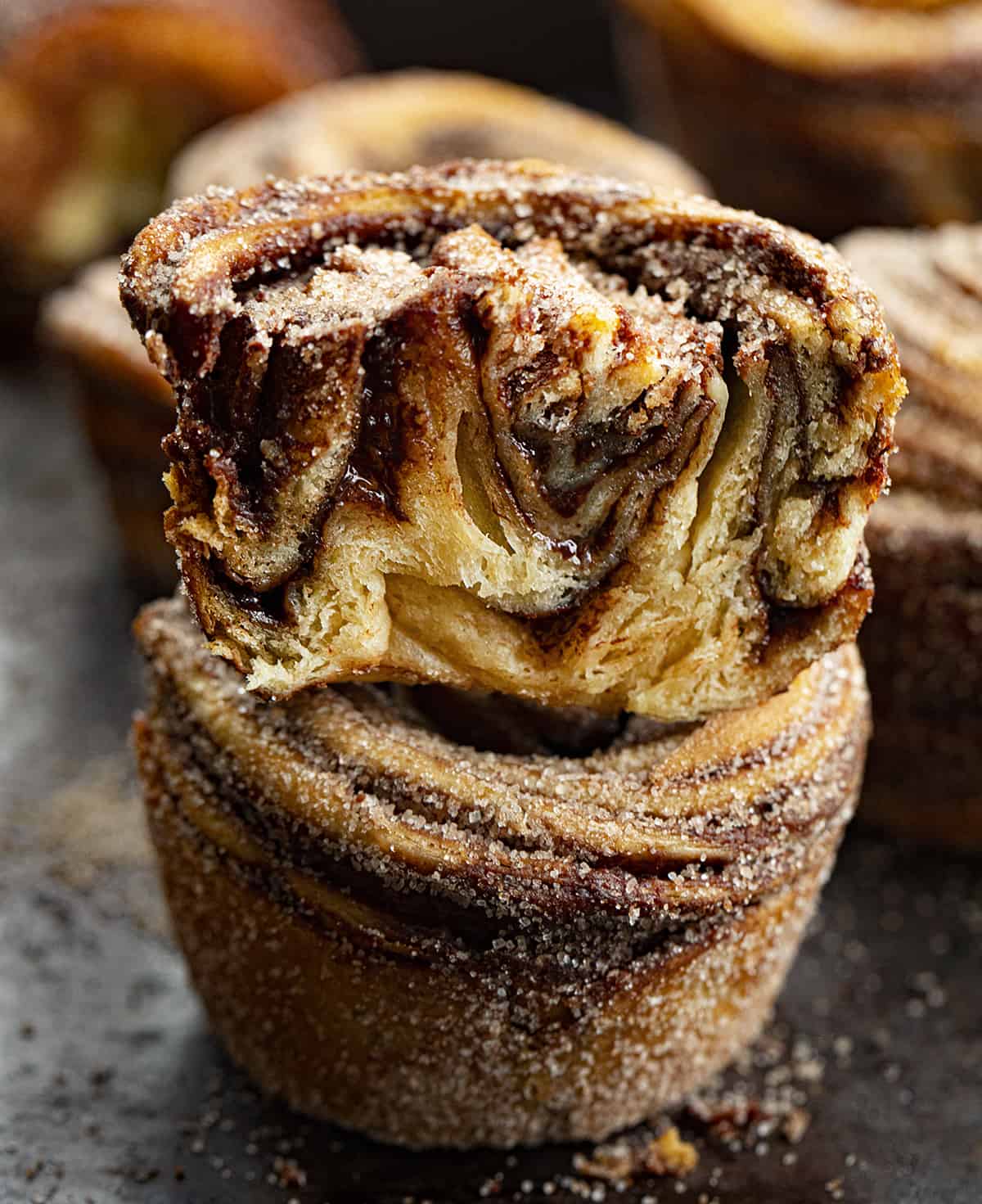 A cruffin is a cross between a croissant and a muffin that is rolled up like a cinnamon roll. It's a buttery, flaky dessert that is easier to make than it looks. Peppermint seems to be a part of the holidays, and these chocolate peppermint cruffins are no exception. In addition to the chocolate peppermint butter, I rolled each cruffin in more cocoa powder and sugar. They look fancy, but they are easy to make! One Chocolate Peppermint Cruffin Cut in Half and Stacked on top of another cruffin.