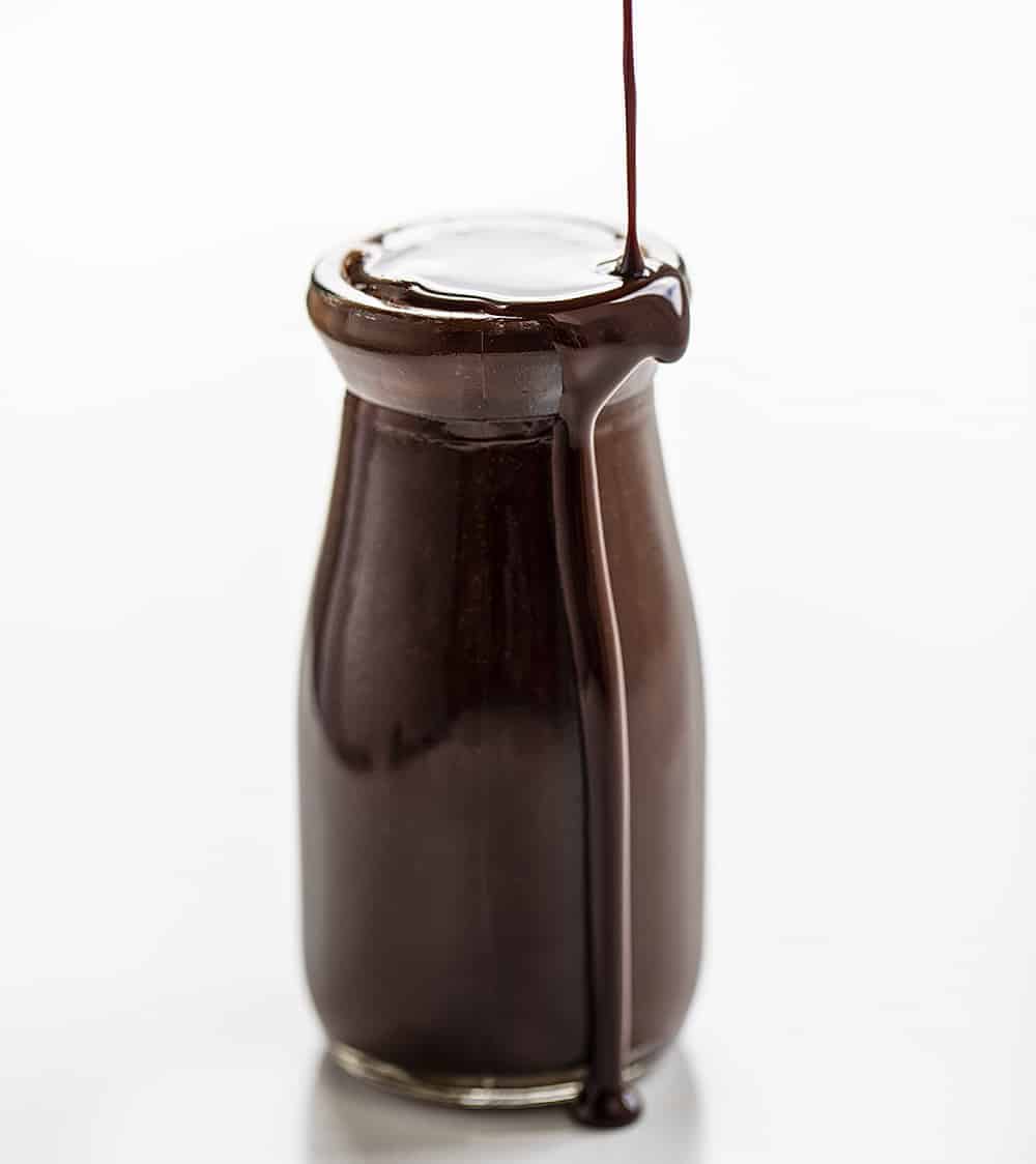 With just a few ingredients, you can have your own supply of chocolate syrup whenever you are craving a topping on your ice cream, dessert, or added to glass of milk for chocolate milk. homemade chocolate syrup, chocolate sauce, chocolate syrup recipe, chocolate milk, Hershey's chocolate syrup, iambaker, i am baker Pouring Chocolate Syrup into Jar and it Spilling Over Edge