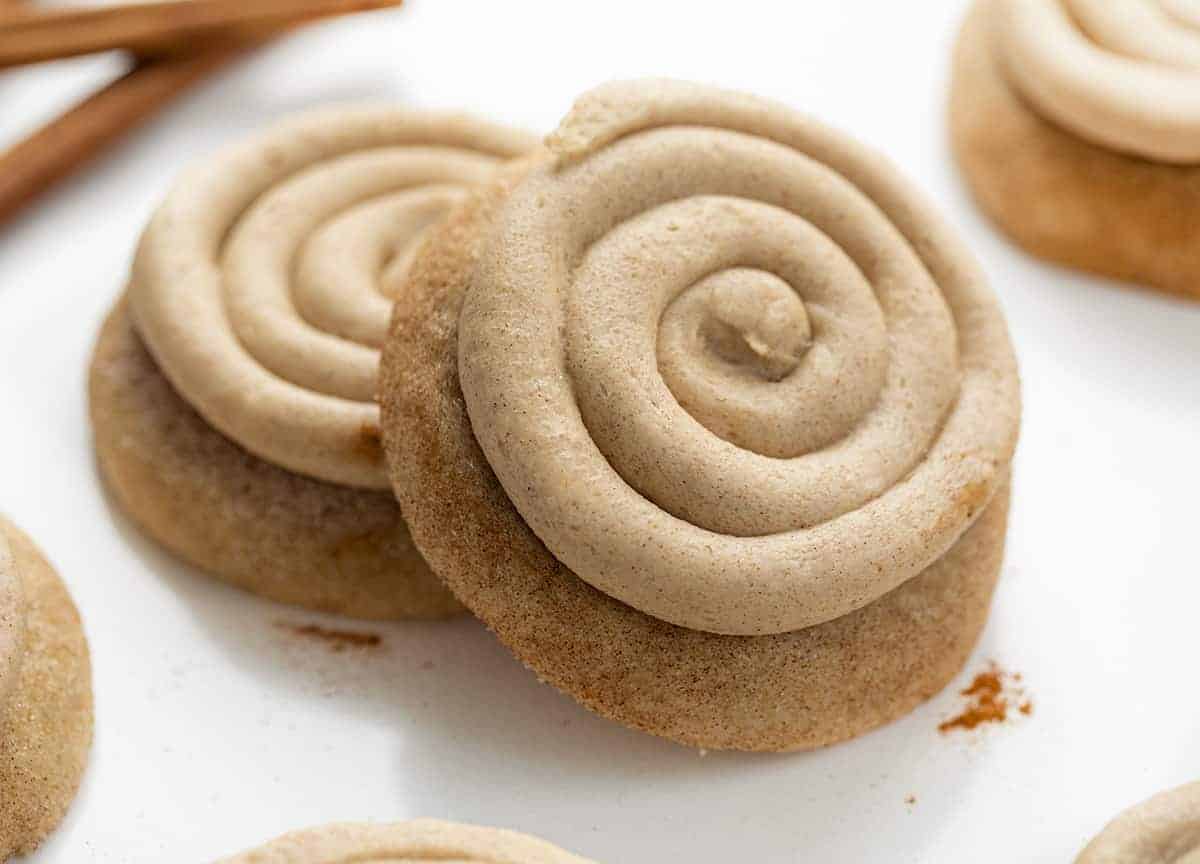 Churro Cookies are a Crumbl cookie copycat that are soft and chewy cinnamon sugar cookies topped with cinnamon buttercream. Copycat Cookies, Churro Cookies, Crumbl Cookie, Cinnamon Cookies, baking, Dessert, Fall Baking, Thanksgiving Cookie, Thanksgiving Dessert Recipes, New Years Dessert Cookies, Soft Cookies, i am baker, iambaker Churro Cookies Stacked on Each Other with Cinnamon Sticks