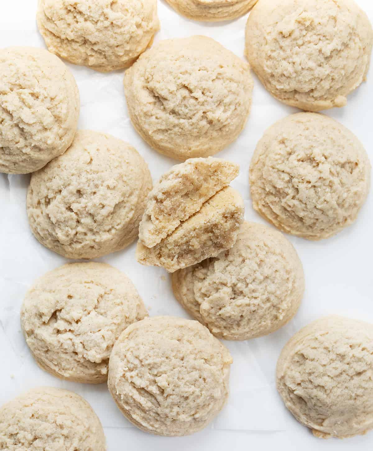Cinnamon Butter Cookies are tender and crumbly cookies that combine the warm flavor of cinnamon and the richness of butter. The sweet buttery flakiness paired with a subtle cinnamon kick is a delectable combination. It's the perfect addition to any cookie exchange, holiday gathering, or Tuesday! Cinnamon Butter Cookies on a White Counter With One Cookie Broken in Half.