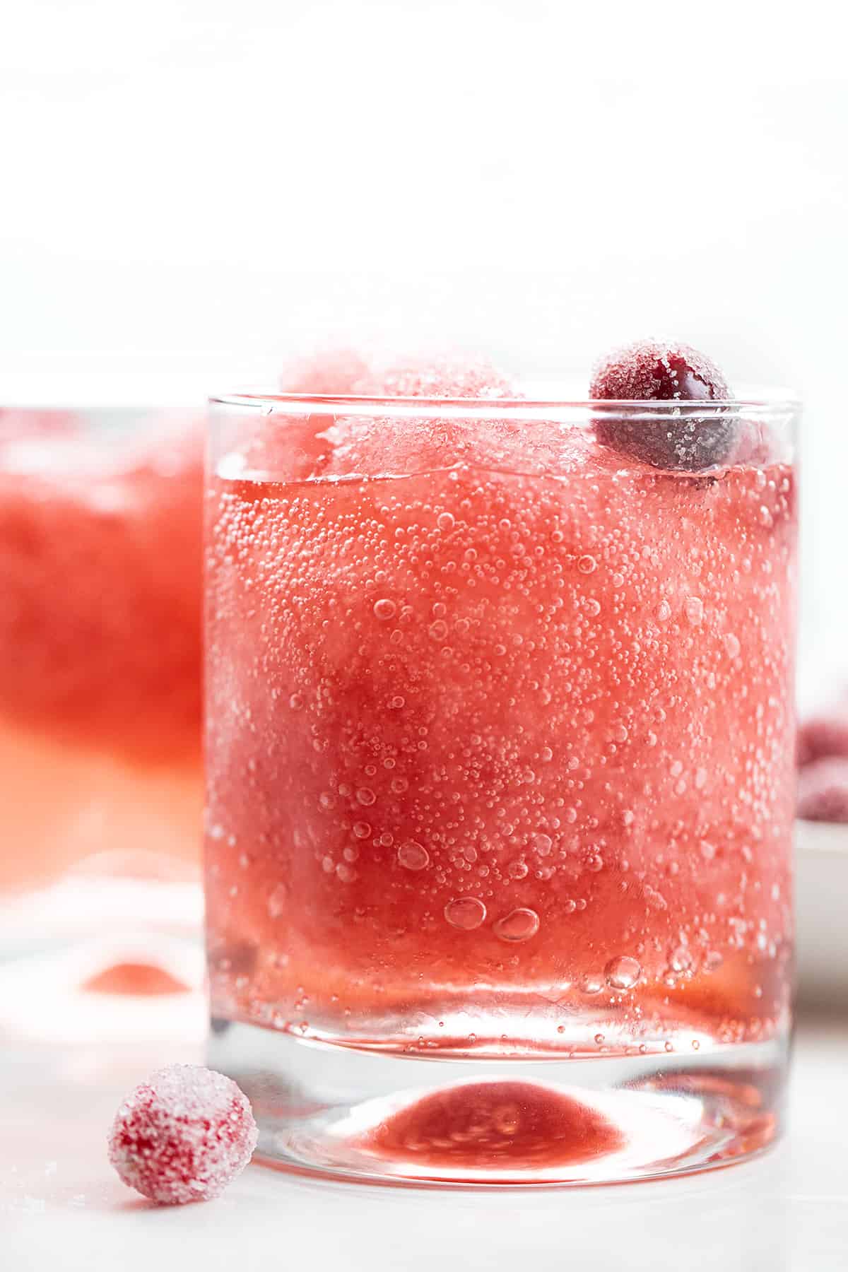 This Cranberry Slush is an adult beverage that is a holiday drink, but would also be delicious in the summertime, so don't forget about it. It's a festive and refreshing drink to serve with a lovely red color from the cranberries. Plus, the lemon-lime soda gives it some carbonation for a few bubbles. Serve it in a large punch bowl and let your guests help themselves! Cheers! Glass of Cranberry Slush with Sugared Cranberries.
