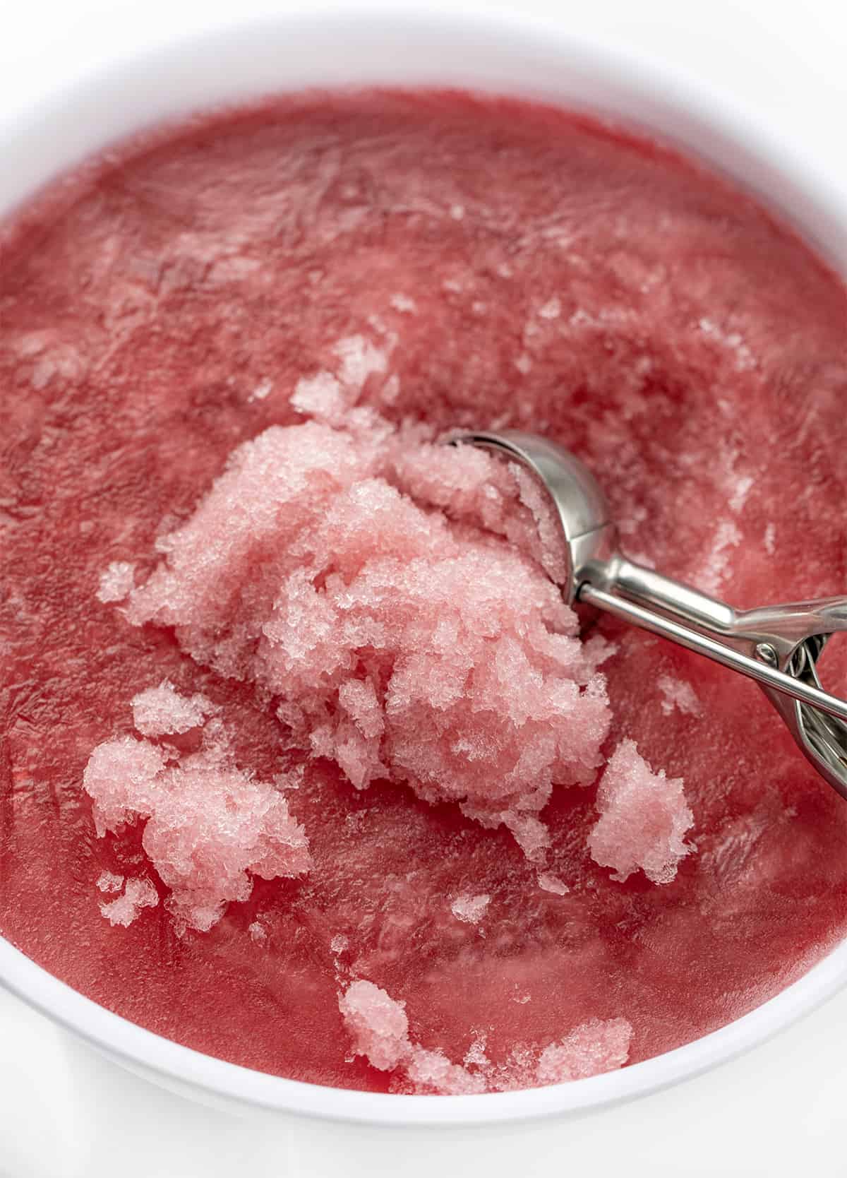 This Cranberry Slush is an adult beverage that is a holiday drink, but would also be delicious in the summertime, so don't forget about it. It's a festive and refreshing drink to serve with a lovely red color from the cranberries. Plus, the lemon-lime soda gives it some carbonation for a few bubbles. Serve it in a large punch bowl and let your guests help themselves! Cheers! Ince Cream Scoop Scooping up Slush form Container of Cranberry Slush.