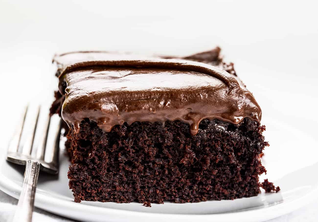 This Chocolate Depression Cake is a moist cake made without any milk, eggs, or butter!! SO DELICIOUS! Depression Cake, Chocolate Depression Cake, Wacky Cake, War Cake, Chocolate Cake, Recipes, Cake, Easy Chocolate Cake, How to Make Chocolate Cake, i am baker, iambaker Chocolate Depression Cake on White PLate with Fork