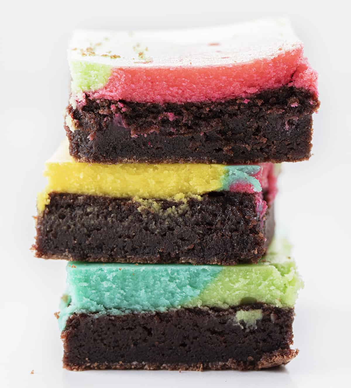 Easter Brownie Bars are a layer of fudgy brownies topped and baked with a colorful cheesecake layer. It is a simple combination of brownie and cheesecake, but made fun with some Easter-inspired colors! Baking, Easter Dessert, Brownies, Colorful Brownies, Chocolate, Chocolate Brownies, Dessert, Cheesecake, food photography, recipes, i am baker, iambaker Stacked of Chocolate Easter Brownies