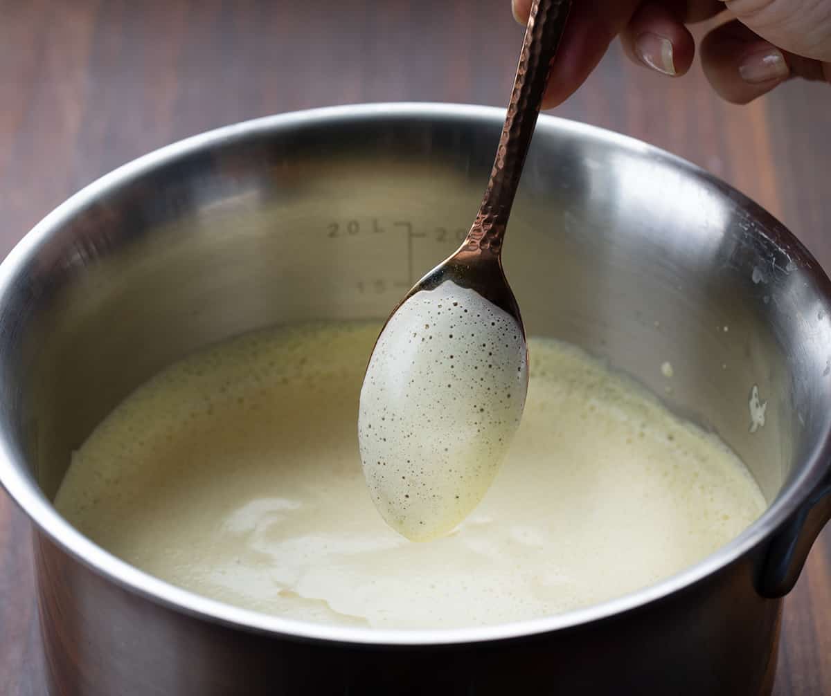 Eggnog is a creamy, egg-yolk-based holiday drink with just the right amount of spice that can be made with or without alcohol. It's delicious either way! And, when you make your own batch, you know exactly what is going into it without all the added preservatives. Better yet, you can adapt the recipe for all ages, making it a Christmas mocktail recipe if you leave out the alcohol. Eggnog mixture coating the back of a spoon.