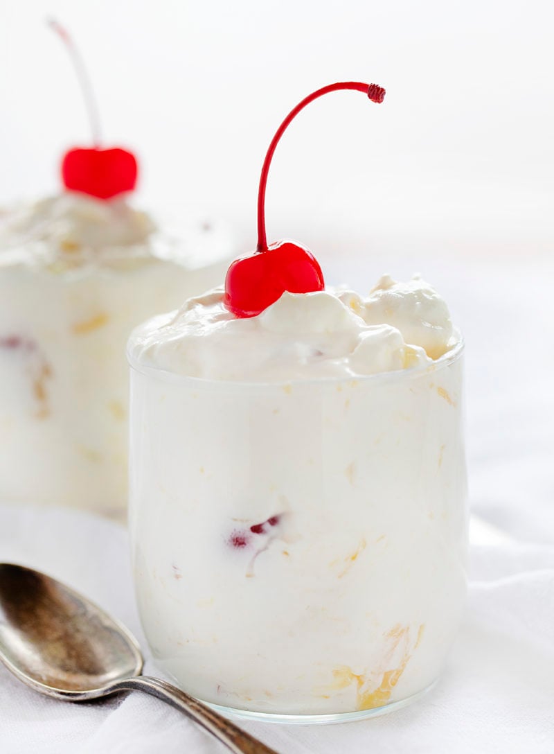 The best no-bake desserts to get your sweet tooth through the summer! no bake, no bake desserts, desserts, recipes, cheesecake, cookies, bars, cake, pudding, mousse, puppy chow, muddie buddies, rice krispy bars, dessert, memorial day dessert, labor day desserts, i am baker, iambaker Pineapple Fluff in Glasses with Spoons and Cherries on Top.