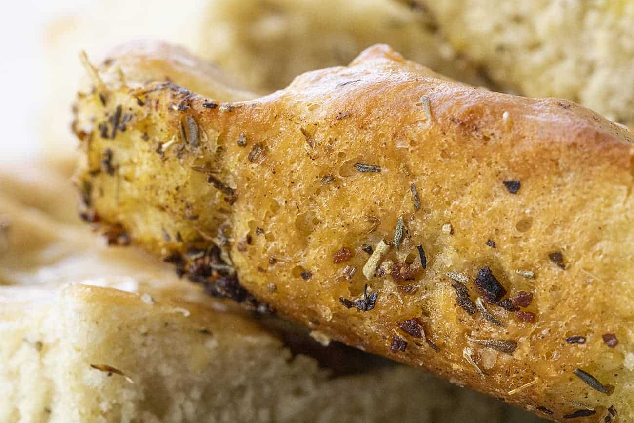 Focaccia Bread is an Italian bread that is made with lots of olive oil and full of Italian seasoning for a delicious and savory snack or appetizer. focaccia bread, bread recipes, Italian bread, i am baker, iambaker, homemade focaccia bread recipe, baking bread Crusty Edge of a Piece of Focaccia Bread