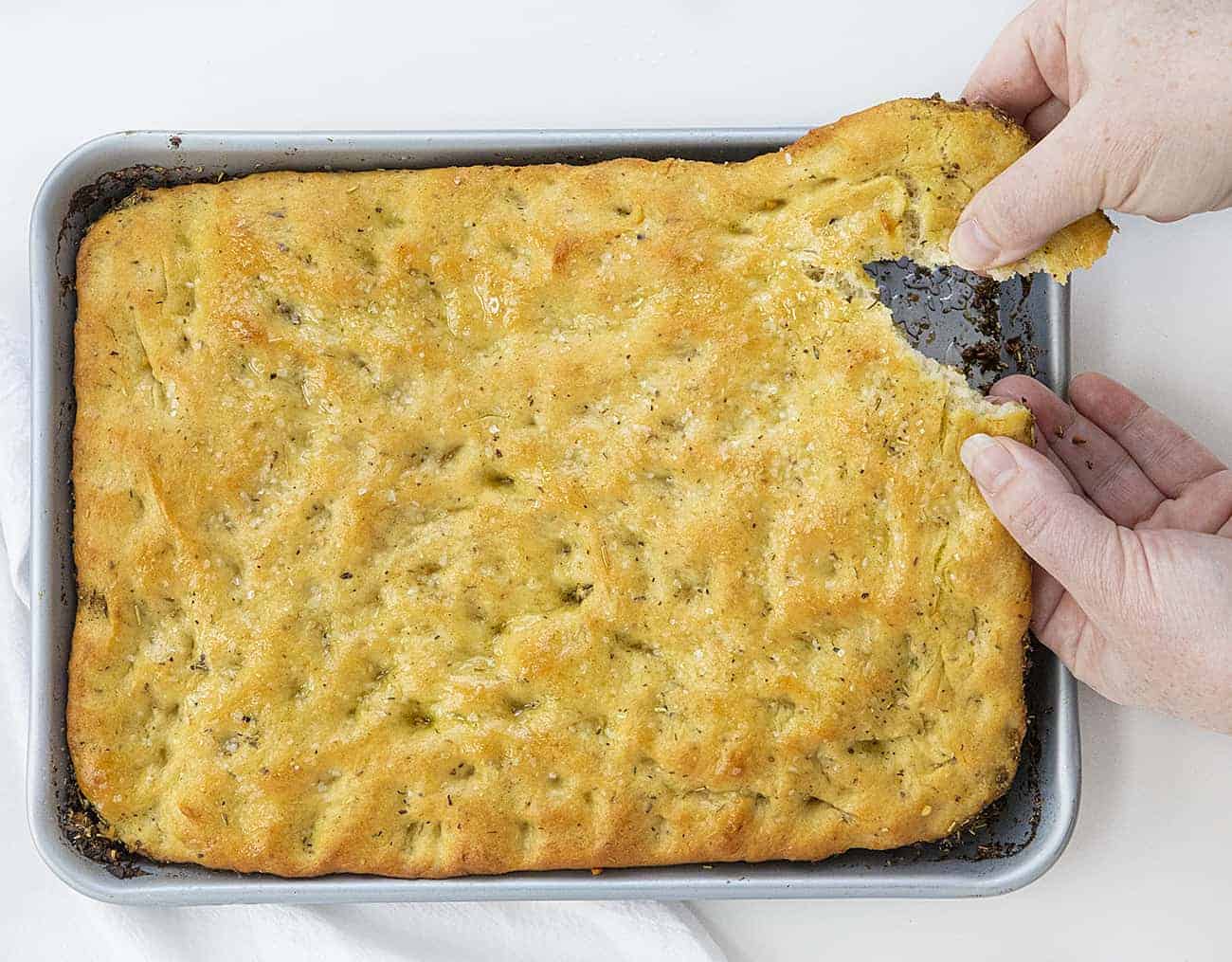 Focaccia Bread is an Italian bread that is made with lots of olive oil and full of Italian seasoning for a delicious and savory snack or appetizer. focaccia bread, bread recipes, Italian bread, i am baker, iambaker, homemade focaccia bread recipe, baking bread Hands Tearing off a Piece of Focaccia Bread