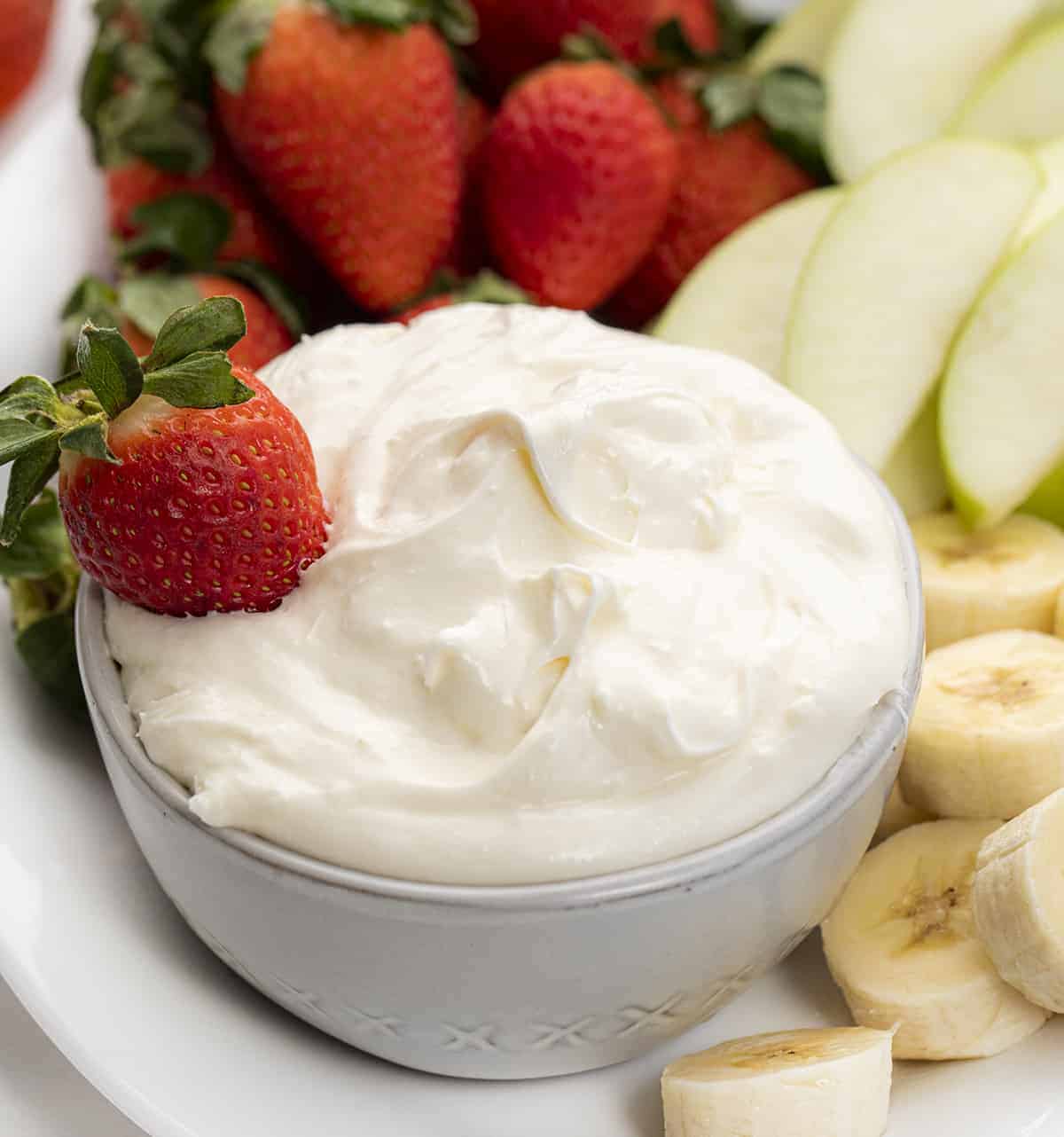 Easy Fruit Dip is a creamy and whipped dip made with cream cheese, marshmallow creme, cool whip, and lemon juice, perfect for dipping fresh fruit. Creamy Fruit Dip, How to Make Fruit Dip, Cream Cheese Fruit Dip, Fresh Fruit with Dip, Appetizer, recipes, no bake dessert, dessert, i am baker, iambaker Bowl of Easy Fruit Dip with a Strawberry.