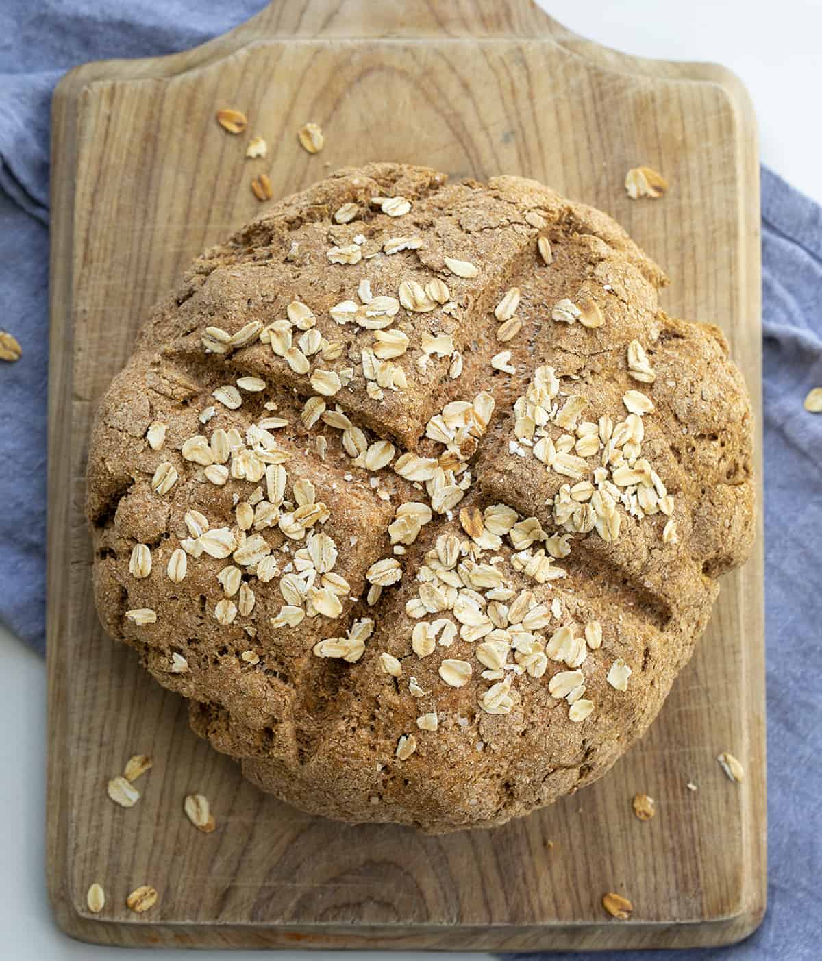 Irish Soda Bread is a dense quick bread that is made with whole wheat flour and bran with old-fashioned oats baked in on top. Irish Soda Bread, How to Make Real Irish Soda Bread, Soda Bread Recipe, Oat Soda Bread, St. Patricks Day, Bread, Recipes, Baking, i am baker, iambaker Irish Soda Bread on a Cutting Board from Overhead