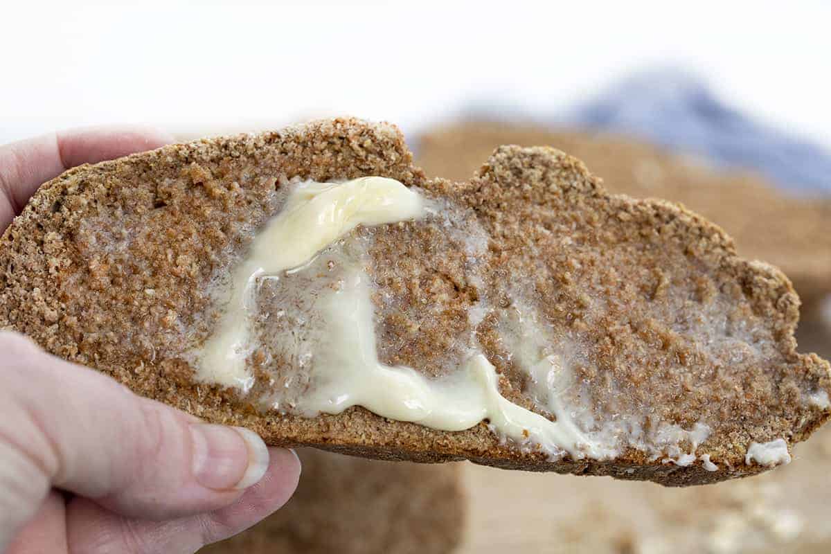 Irish Soda Bread is a dense quick bread that is made with whole wheat flour and bran with old-fashioned oats baked in on top. Irish Soda Bread, How to Make Real Irish Soda Bread, Soda Bread Recipe, Oat Soda Bread, St. Patricks Day, Bread, Recipes, Baking, i am baker, iambaker Hand Holding Piece of Irish Soda Bread with Butter Melting on It