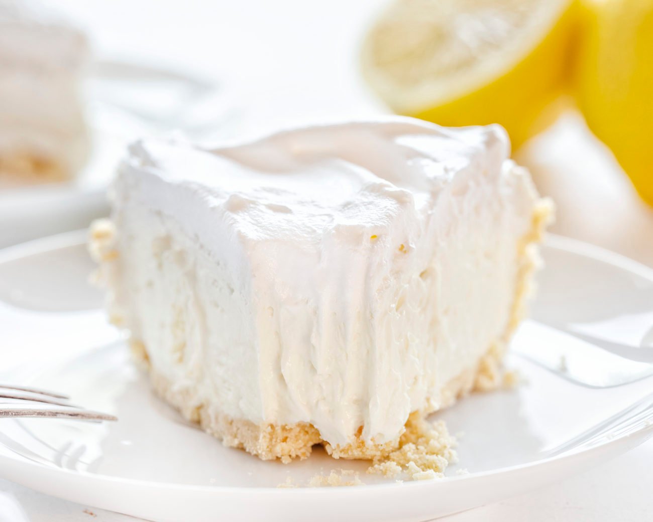 The best no-bake desserts to get your sweet tooth through the summer! no bake, no bake desserts, desserts, recipes, cheesecake, cookies, bars, cake, pudding, mousse, puppy chow, muddie buddies, rice krispy bars, dessert, memorial day dessert, labor day desserts, i am baker, iambaker Lemon Mousse Pie on a Plate with a Bite Removed with a Fork.
