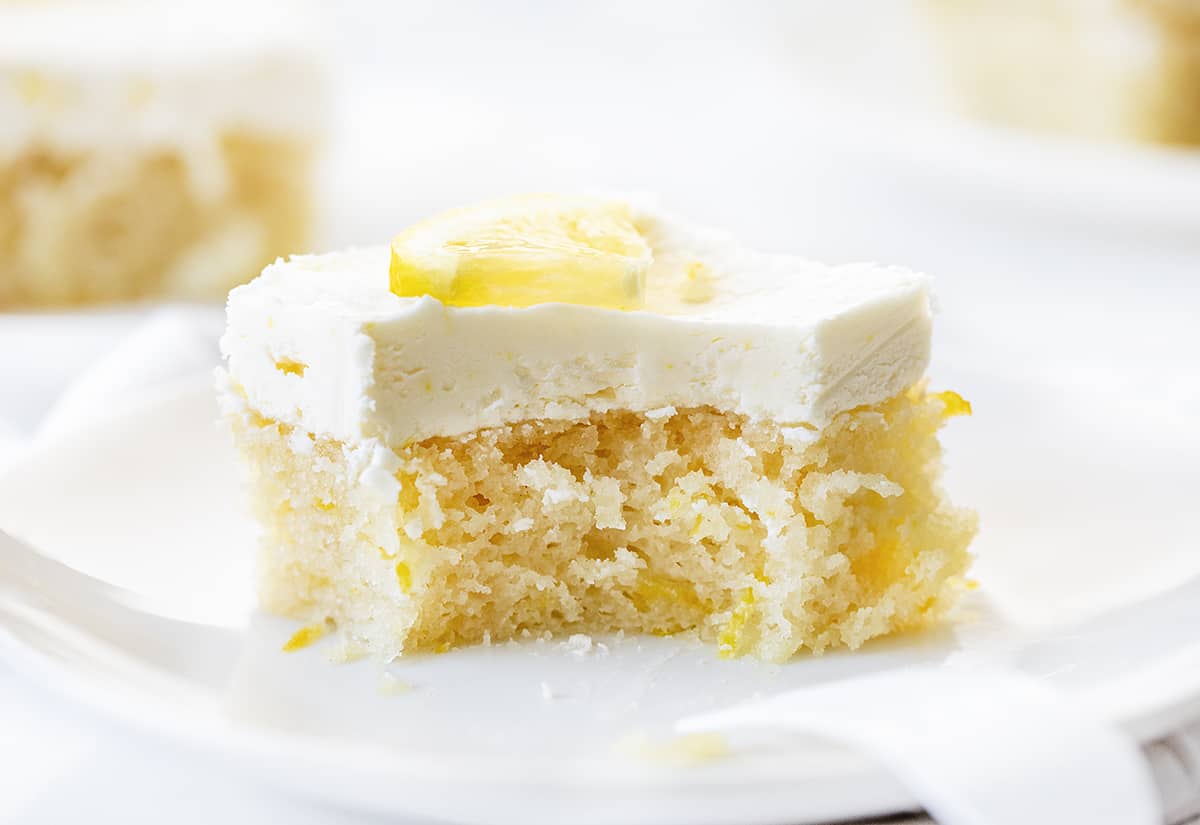 Lemon Crazy Cake is a cake made without milk, eggs, or butter, but full of lemon flavor with a light and fluffy lemon buttercream on top. Lemon Depression Cake, Lemon Wacky Cake, Crazy Cake, Wacky Cake, Depression Cake, Cake with No Milk, Lemon Cake with No Eggs, Lemon Cake with No Butter, Dairy Free Lemon Cake, Desserts, Baking, Summer time desserts, lemon buttercream, recipes, i am baker, iambaker Piece of Lemon Crazy Cake with a Bite Taken Out and Fork Resting on Plate.