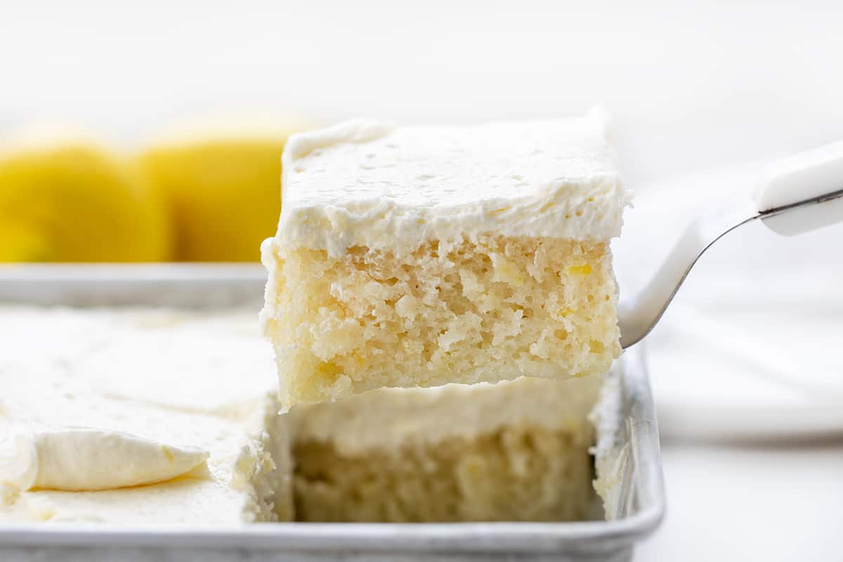 Lemon Crazy Cake is a cake made without milk, eggs, or butter, but full of lemon flavor with a light and fluffy lemon buttercream on top. Lemon Depression Cake, Lemon Wacky Cake, Crazy Cake, Wacky Cake, Depression Cake, Cake with No Milk, Lemon Cake with No Eggs, Lemon Cake with No Butter, Dairy Free Lemon Cake, Desserts, Baking, Summer time desserts, lemon buttercream, recipes, i am baker, iambaker Spatula Picking up a Piece of Lemon Crazy Cake from Pan.