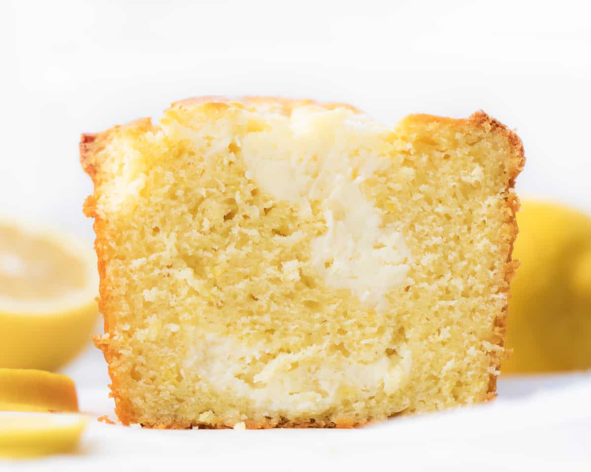 Lemon Cream Cheese Loaf is a moist and tender cake bursting with lemon flavor with a rich cream cheese swirl. It is delicious and visually stunning, with a beautiful marbled pattern from the swirl. It's a delightful option for breakfast, brunch, a sweet snack, or dessert! Sliced Lemon Cream Cheese Loaf with Lemons Around It.