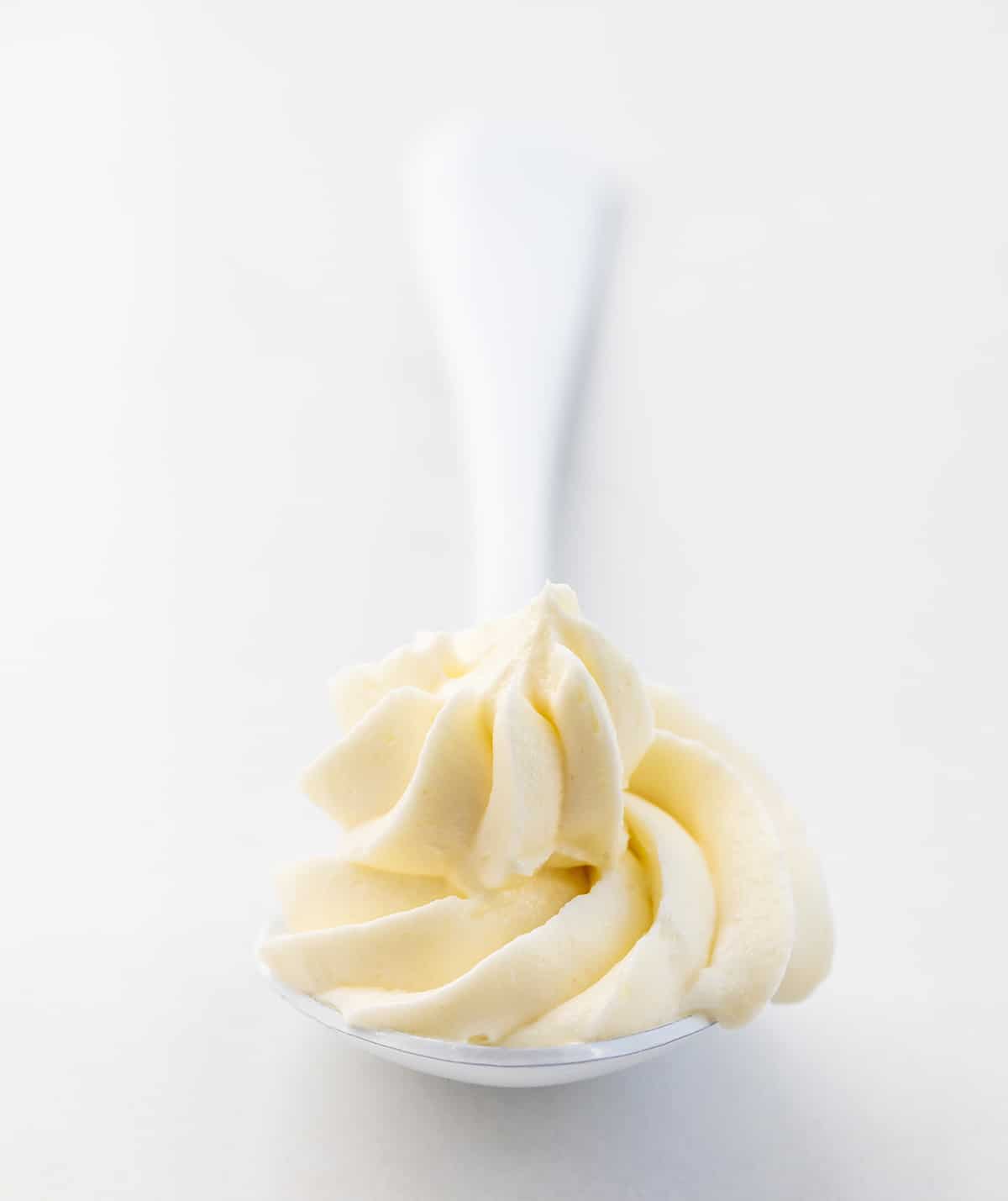 Lemon Ermine Frosting is a smooth, creamy, and buttery frosting made with a cooked lemon juice and flour mixture for just the right lemony zing in every taste. It has a smooth-as-silk texture and a POP of bright lemon tartness that pairs so well with the subtle sweetness of classic ermine frosting. It will give many baked goods a bright lemon flavor! It is perfect for piping and frosting cakes! Spoonful of Lemon Ermine Frosting.