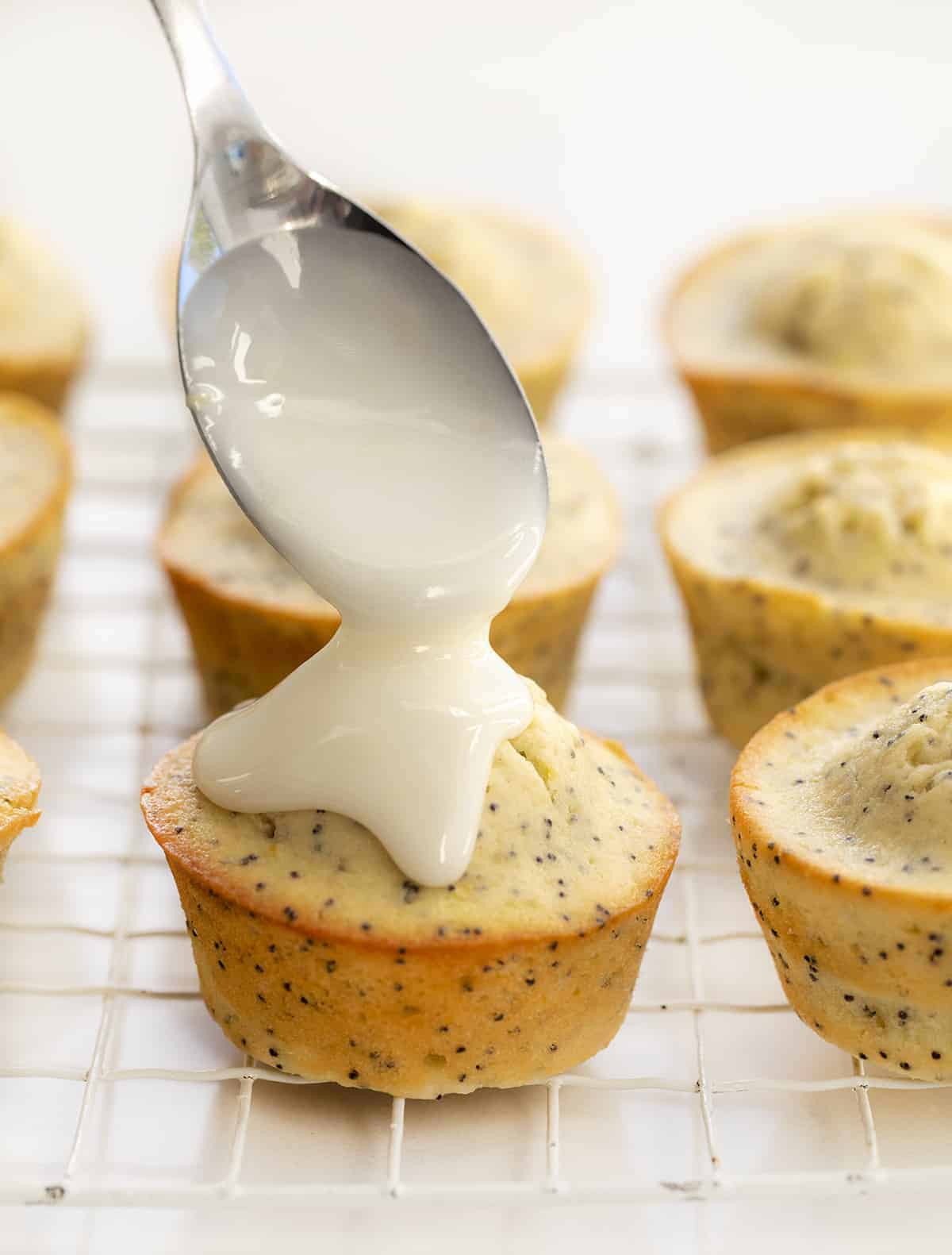 Lemon Poppy Seed Muffins are moist muffins made with lemon juice, lemon zest, and poppy seeds and then topped with a lemon glaze. Muffins, Breakfast, Poppy Seed Muffins, Lemon Poppy Seed, recipes, baking, glaze, i am baker, iambaker Drizzling Glaze of Lemon Poppy Seed Muffins