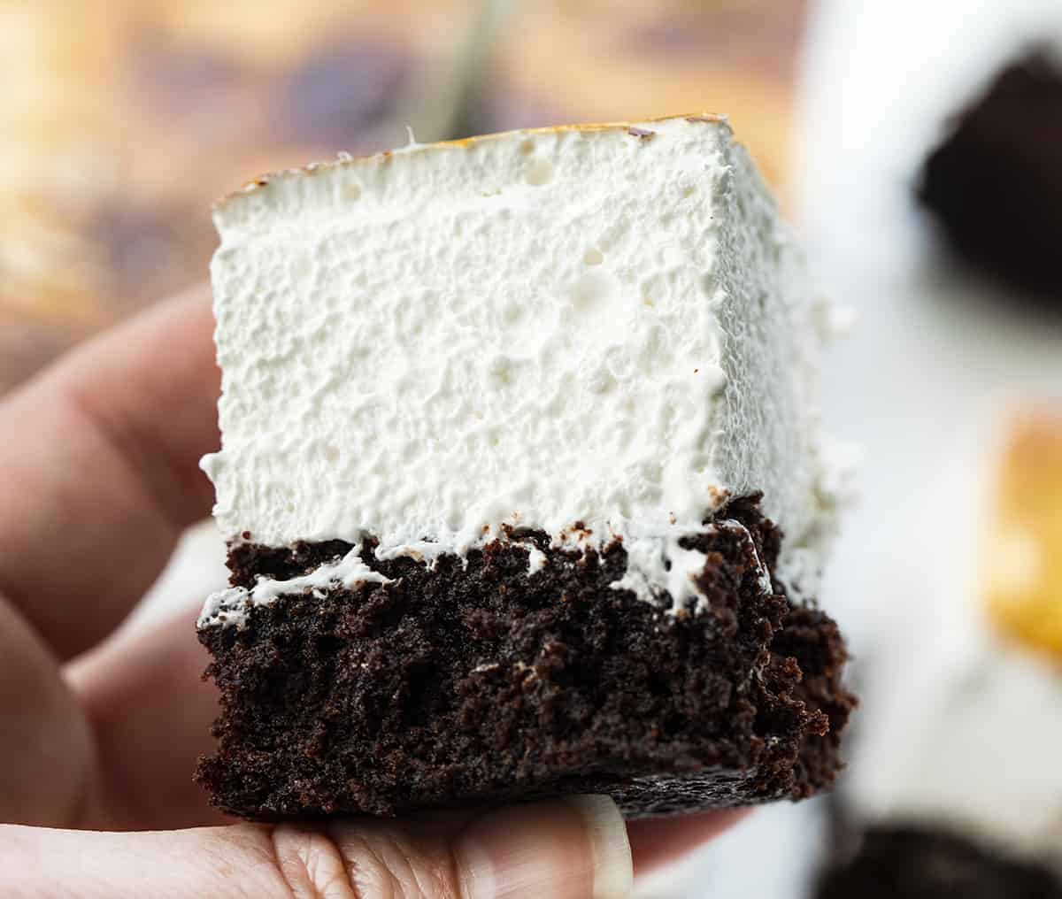 Toasted Marshmallow Brownies are a layer of baked brownies that are topped with homemade marshmallow that is toasted to a golden brown. Brownie Recipes, Homemade Marshmallow, How to Make Marshmallow, Toasted Marshmallow, Baking, Dessert, BBQ Dessert, cookout desserts, campfire, recipes, i am baker, iambaker Hand Holding Toasted Marshmallow Brownie