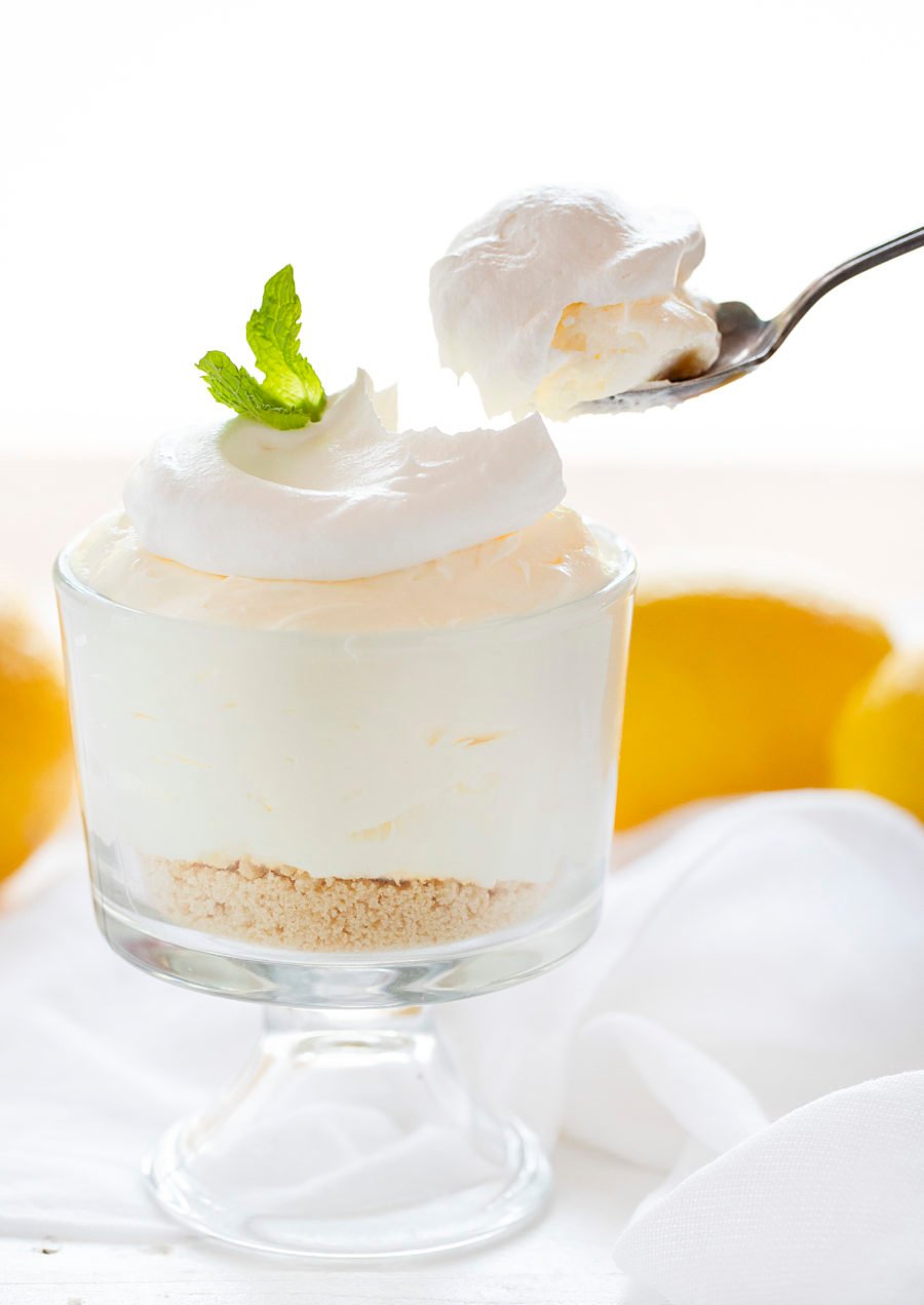 The best no-bake desserts to get your sweet tooth through the summer! no bake, no bake desserts, desserts, recipes, cheesecake, cookies, bars, cake, pudding, mousse, puppy chow, muddie buddies, rice krispy bars, dessert, memorial day dessert, labor day desserts, i am baker, iambaker Lemon Mousse in a Parfait Glass with Spoon Removing a Bite.